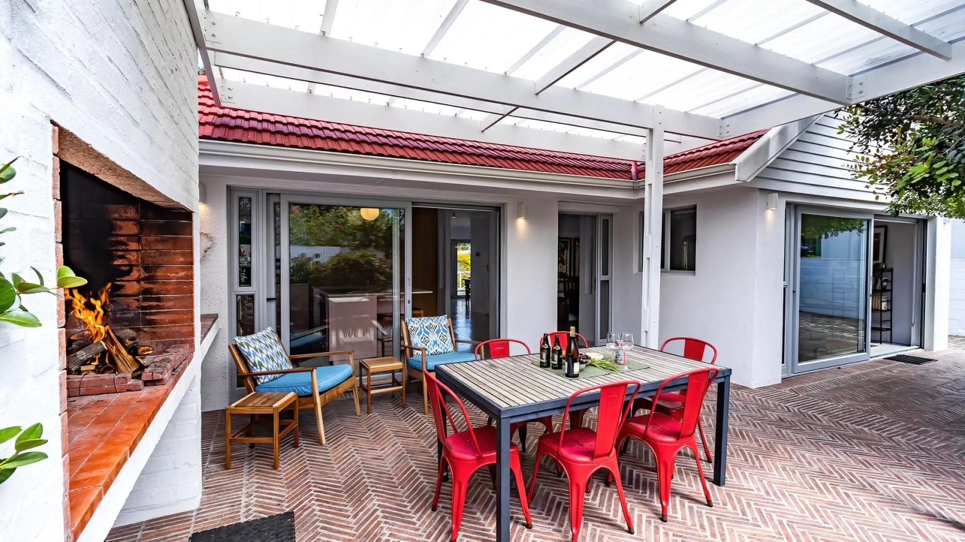 Outdoor patio with fireplace, dining table, and chairs under a pergola.