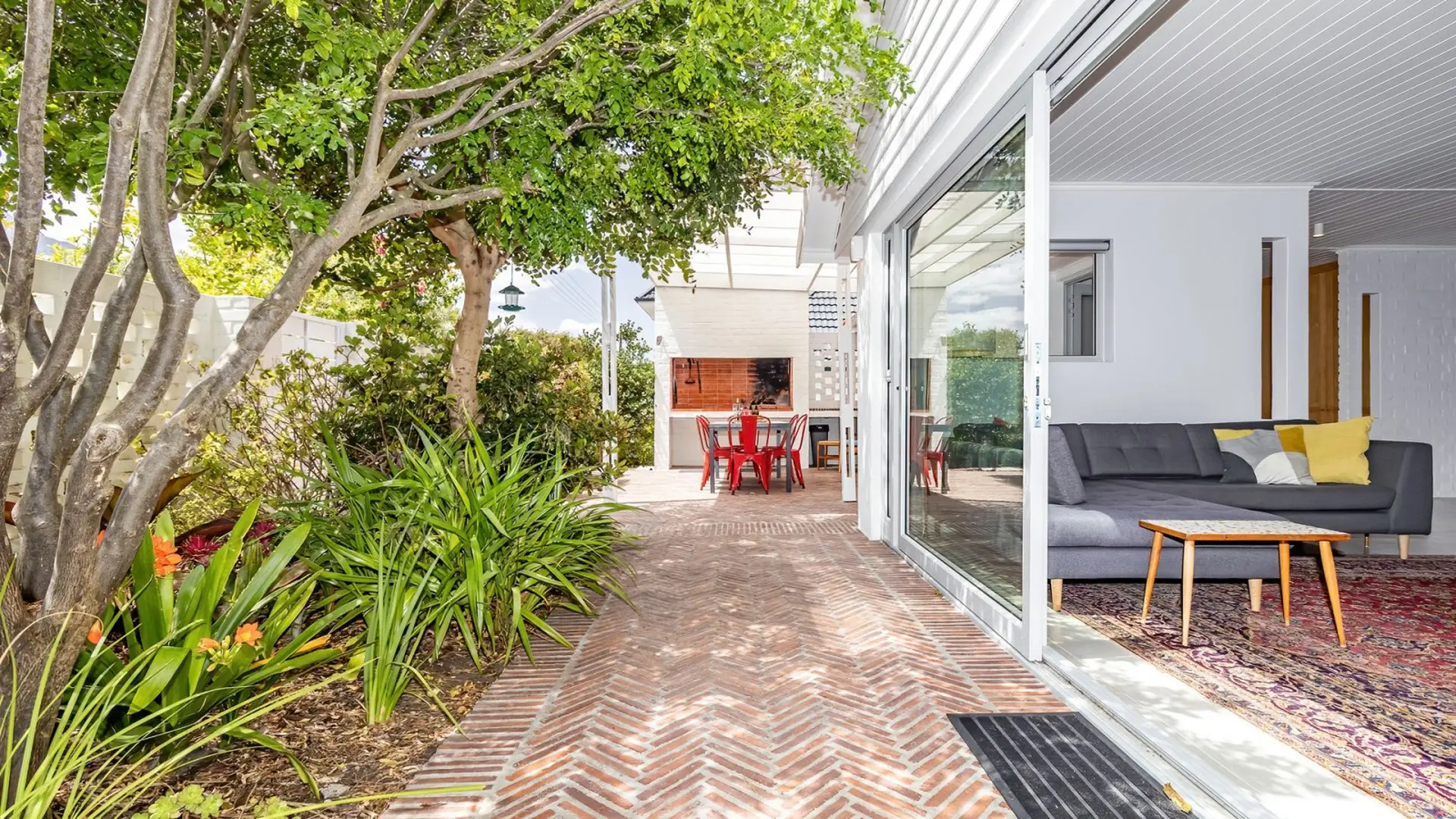 Modern outdoor living space with seating, dining area, and lush greenery.