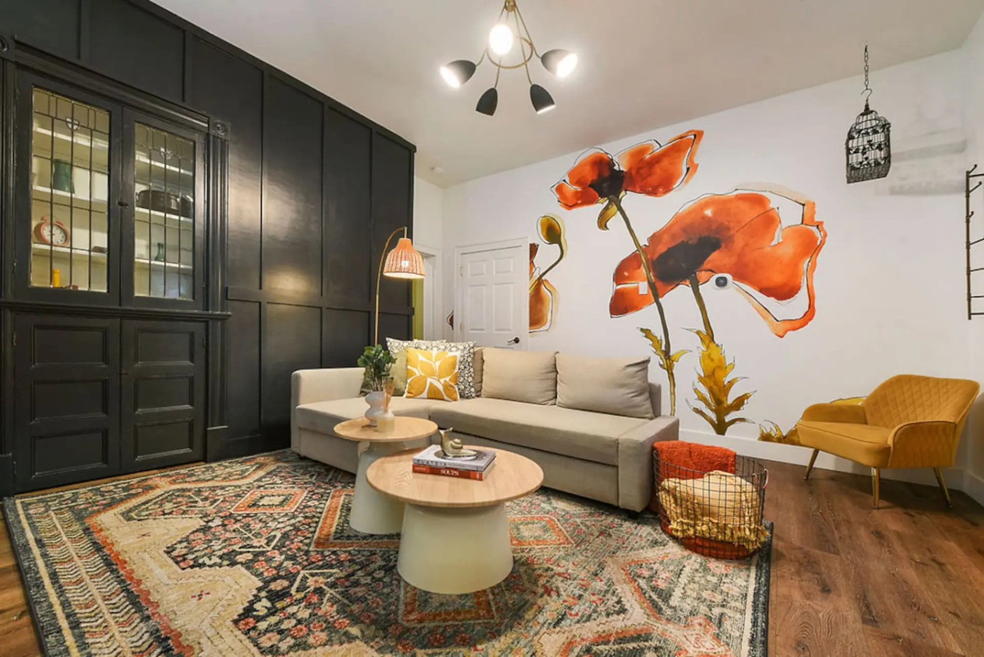 Living room with poppy mural, sofa, arm chair, and oriental rug.