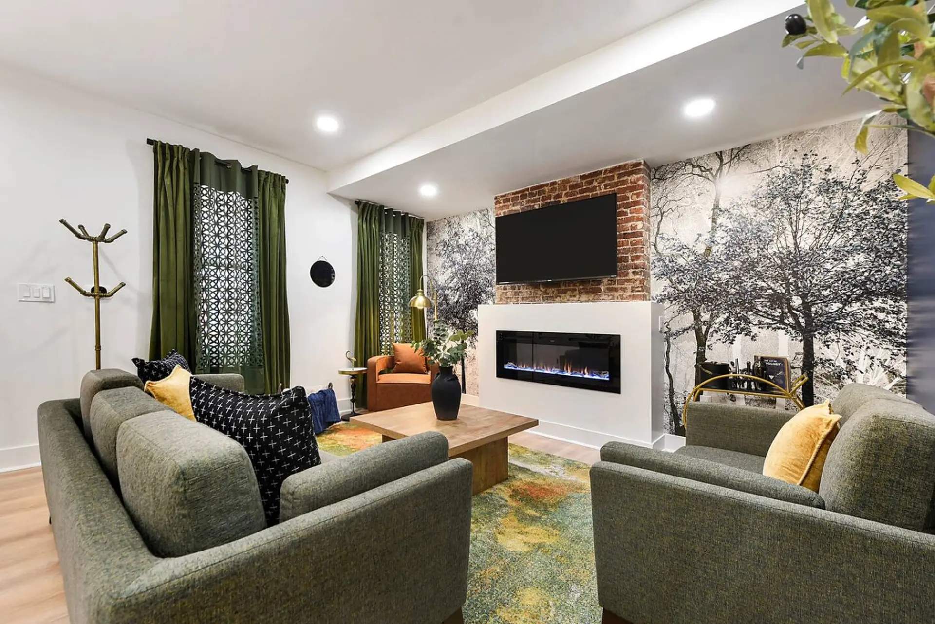 Living room with grey sofas, fireplace, TV, and tree-themed wallpaper.