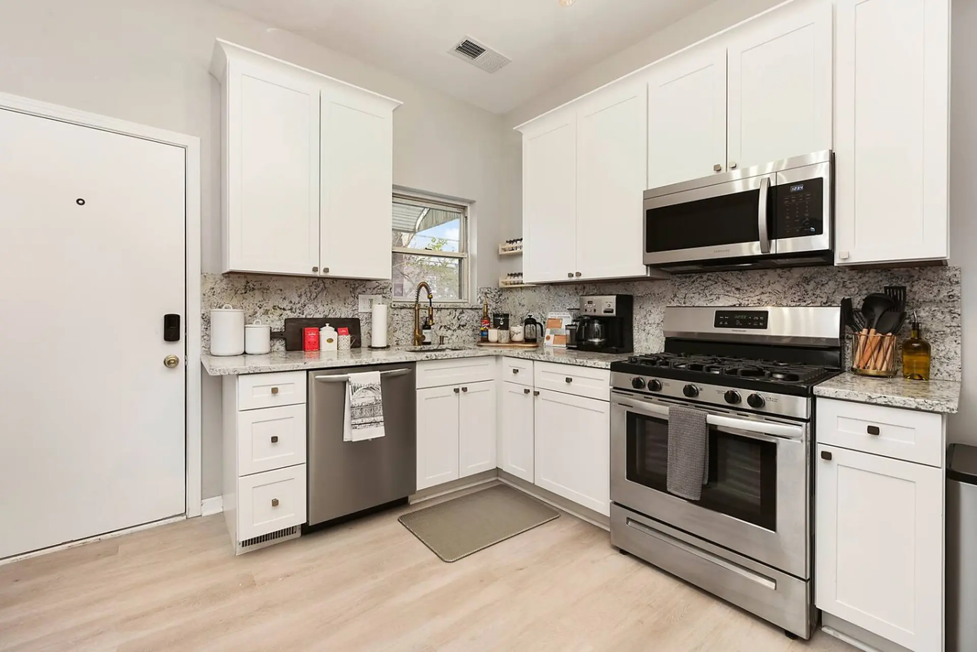 A bright kitchen with white cabinets, granite countertops, and stainless steel appliances.