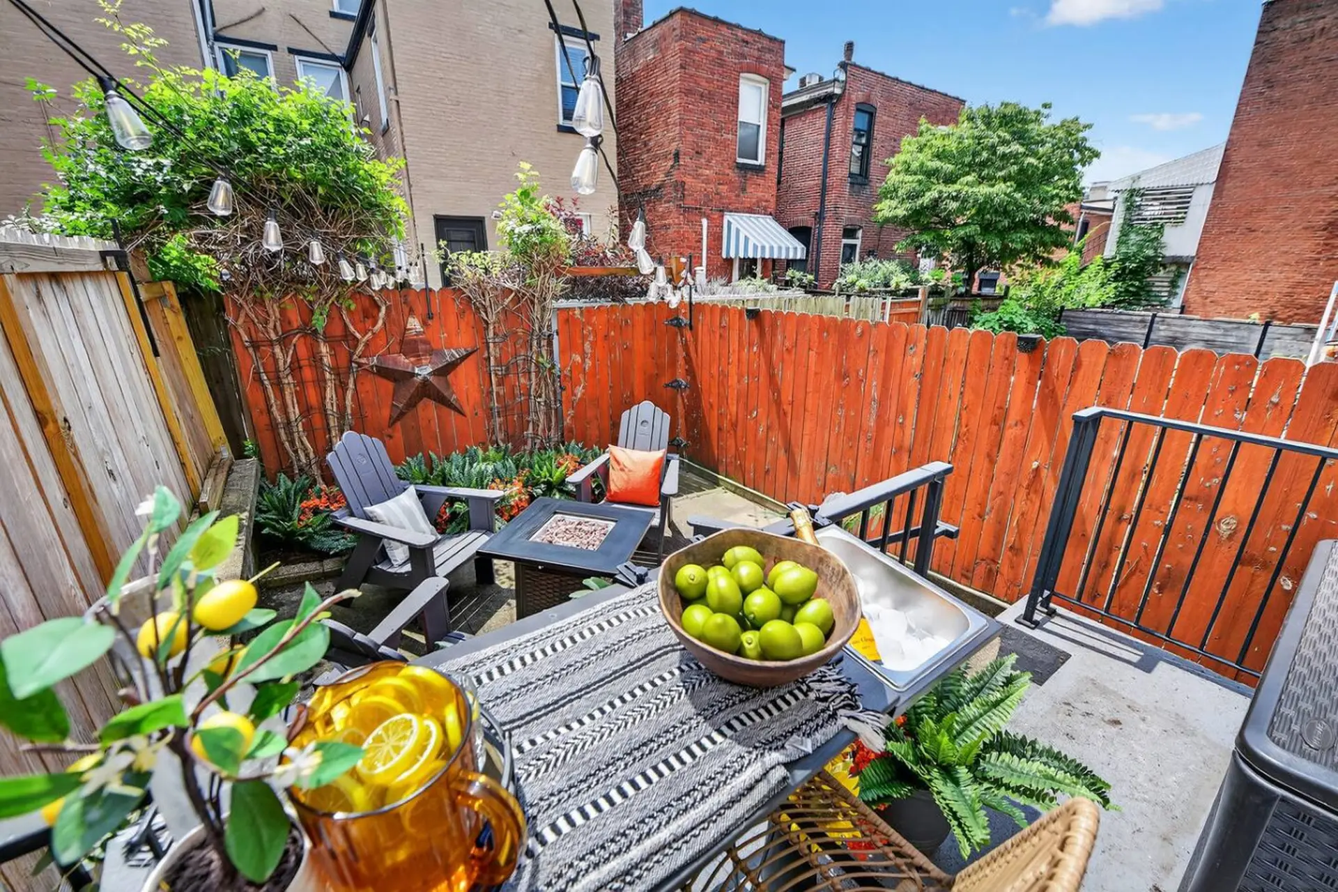 Backyard patio with furniture, fire pit, plants, and drinks.