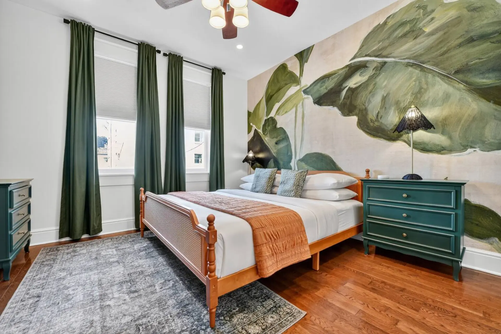 Bedroom with a king size bed, botanical mural, and plush rug.