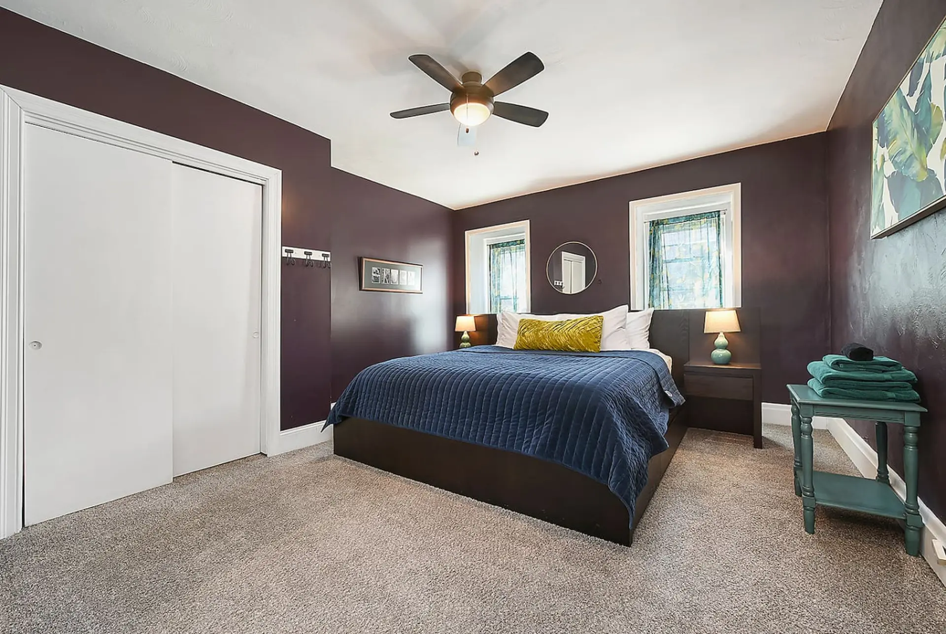 A dark purple bedroom with a large bed, nightstands, and a closet.