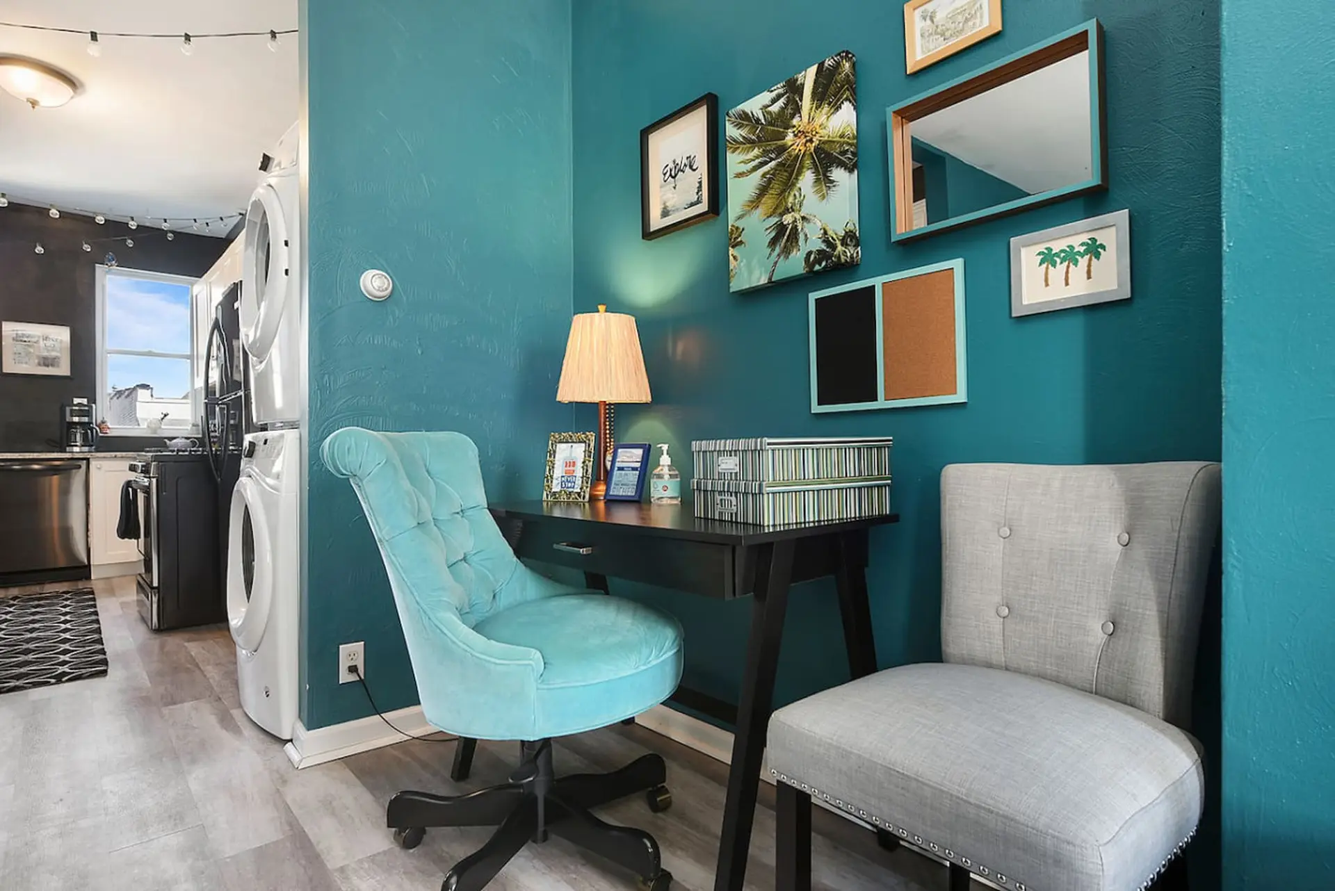 A teal accent wall surrounds a black desk with a teal chair.