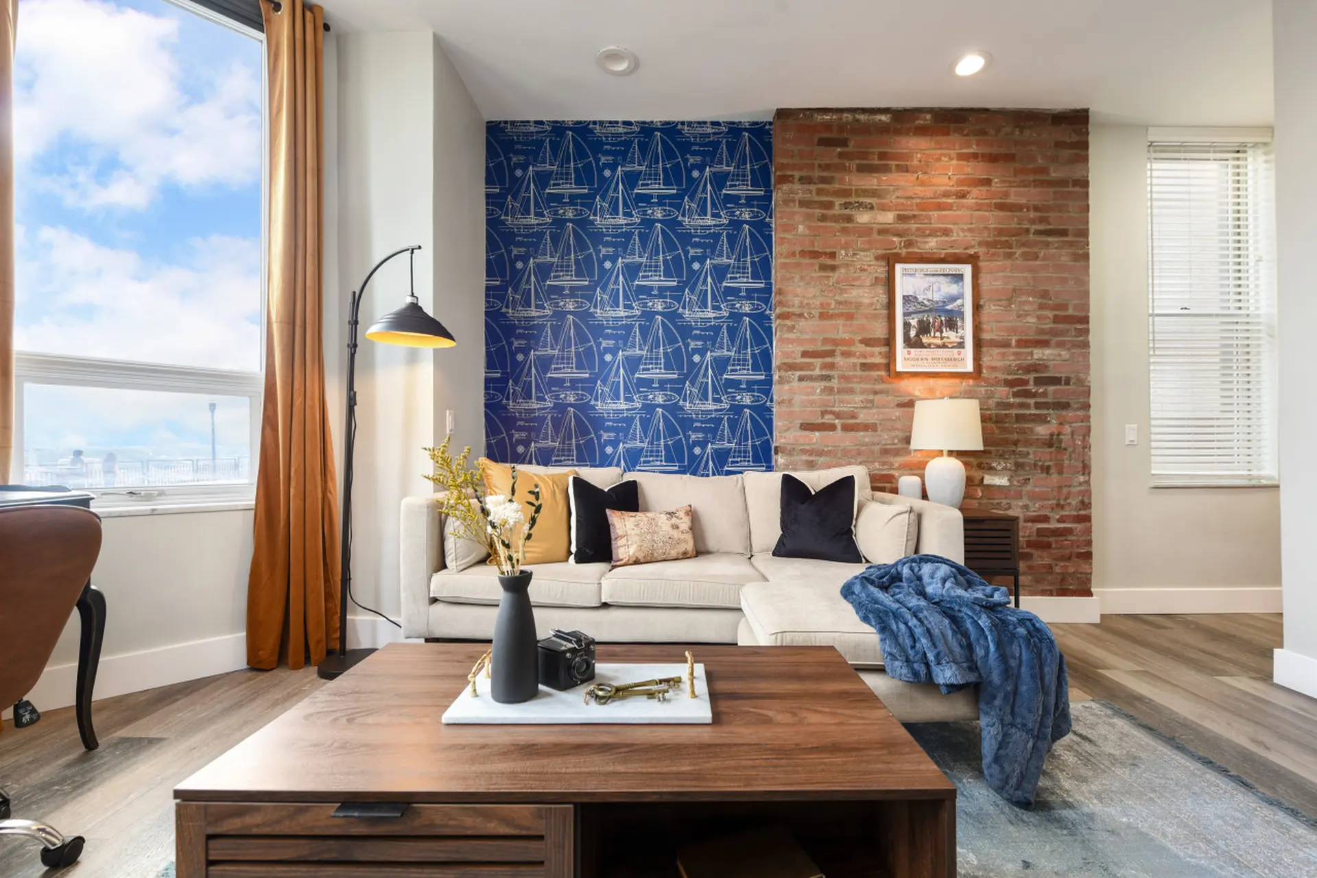 Living room with sectional couch, coffee table with decor, and a window with view.