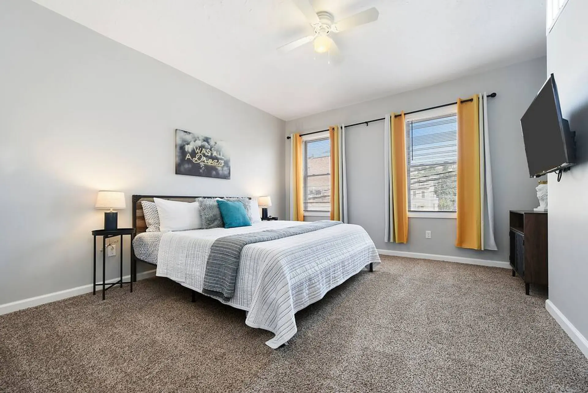 A king-size bed with white bedding and grey accents is in a bedroom.