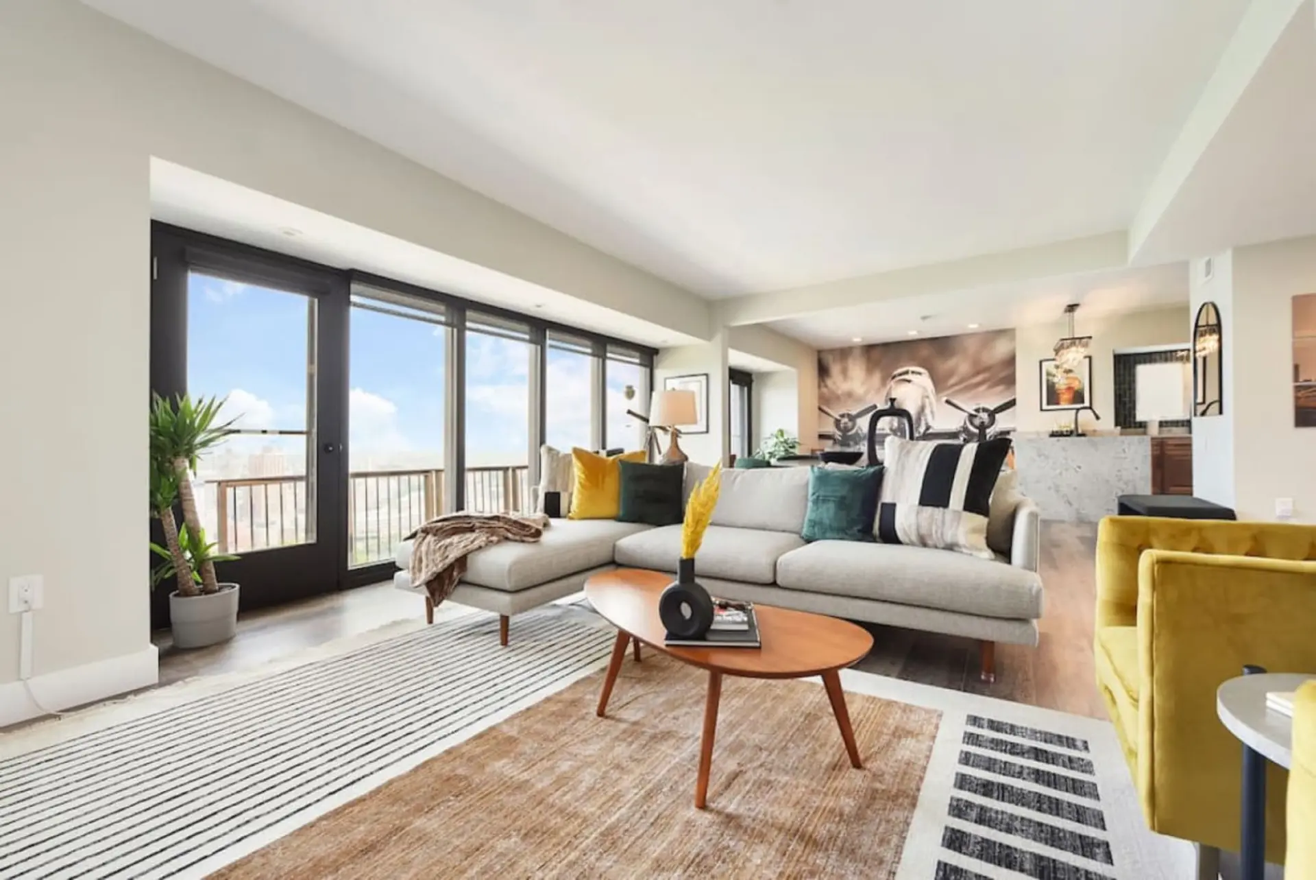 Modern living room with a sectional sofa, airplane mural, and large windows.