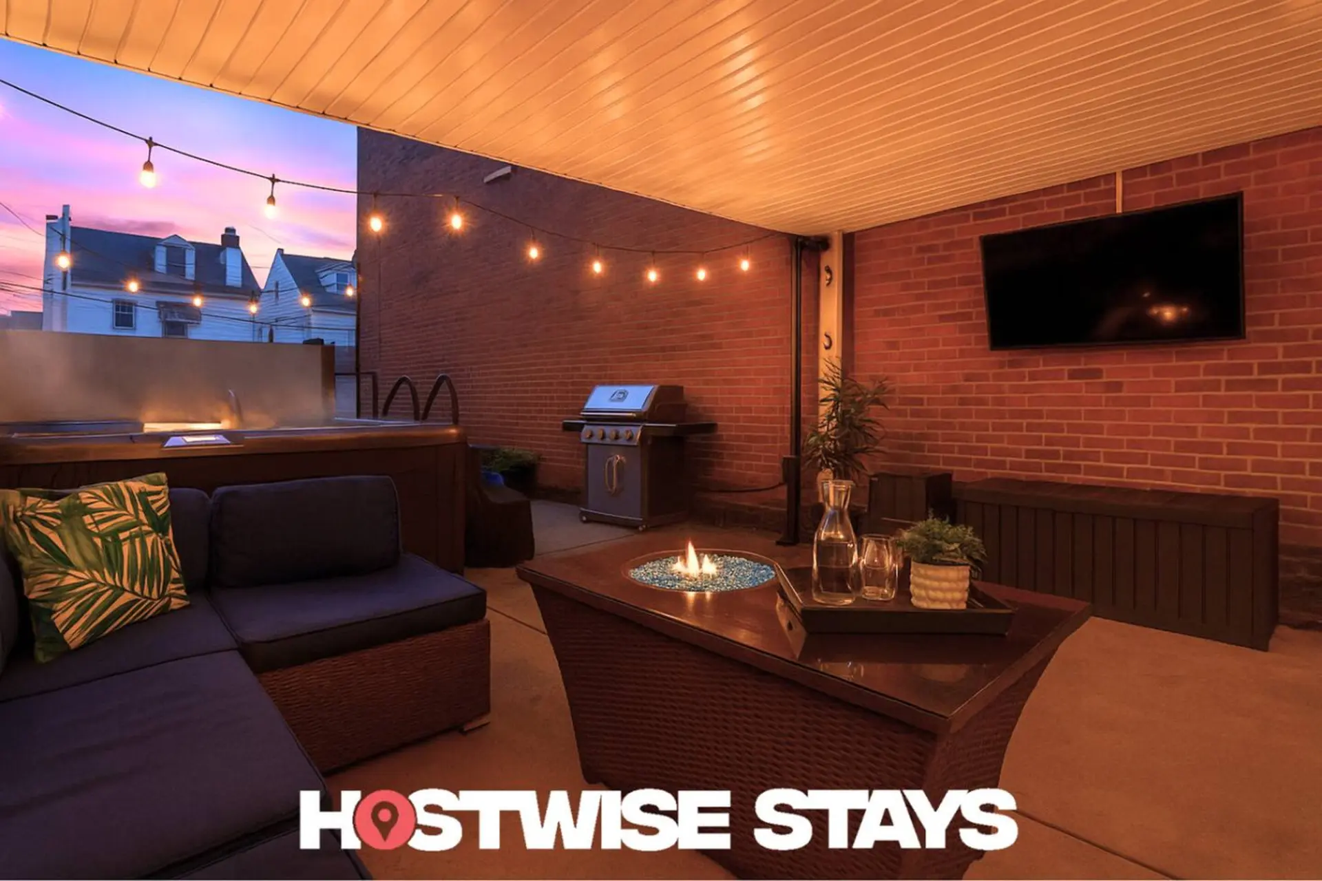 Covered patio with hot tub, grill, fire pit, sectional couch, and TV.