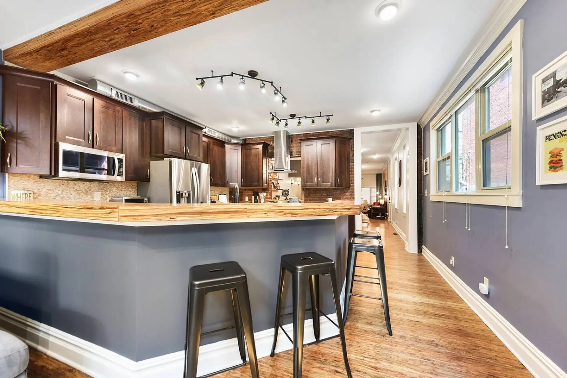 Kitchen with dark wood cabinets, stainless steel appliances, and a wood countertop bar with stools.