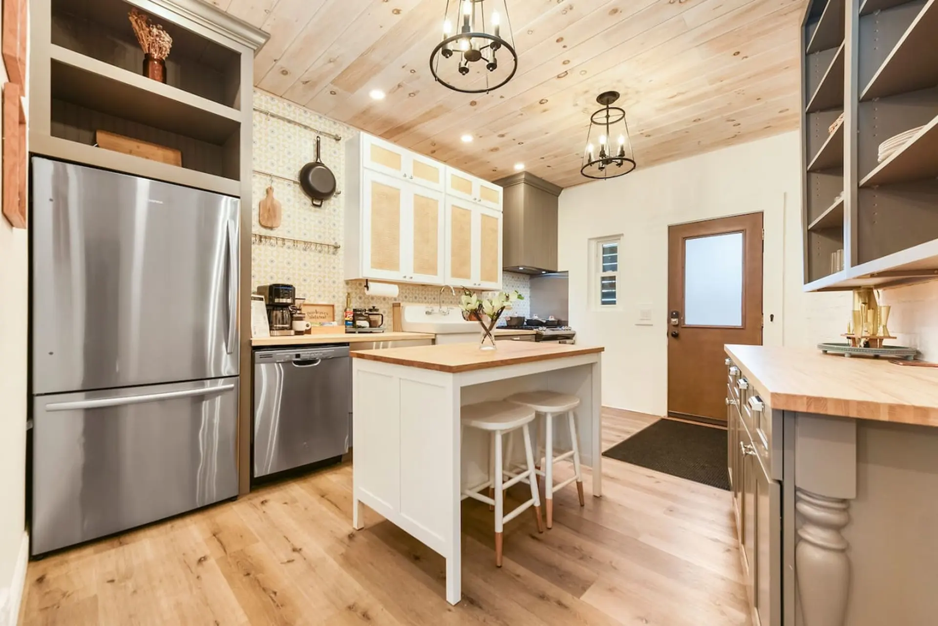 Modern kitchen with stainless steel appliances, wooden countertops, and a wooden plank ceiling.