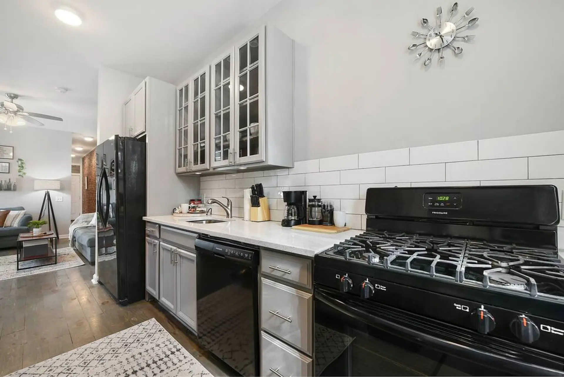 A stylish kitchen with a black gas stove, white subway tile backsplash, and gray cabinets.