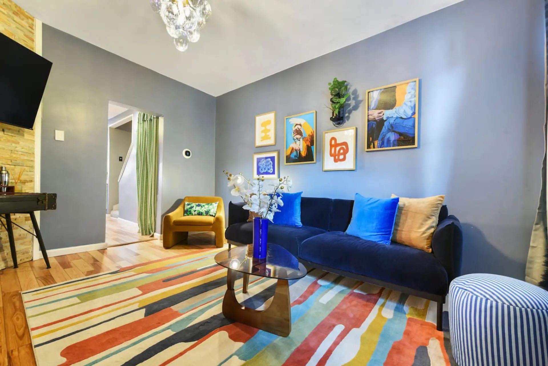 A stylish living room with a navy sofa, colorful rug, and modern art.