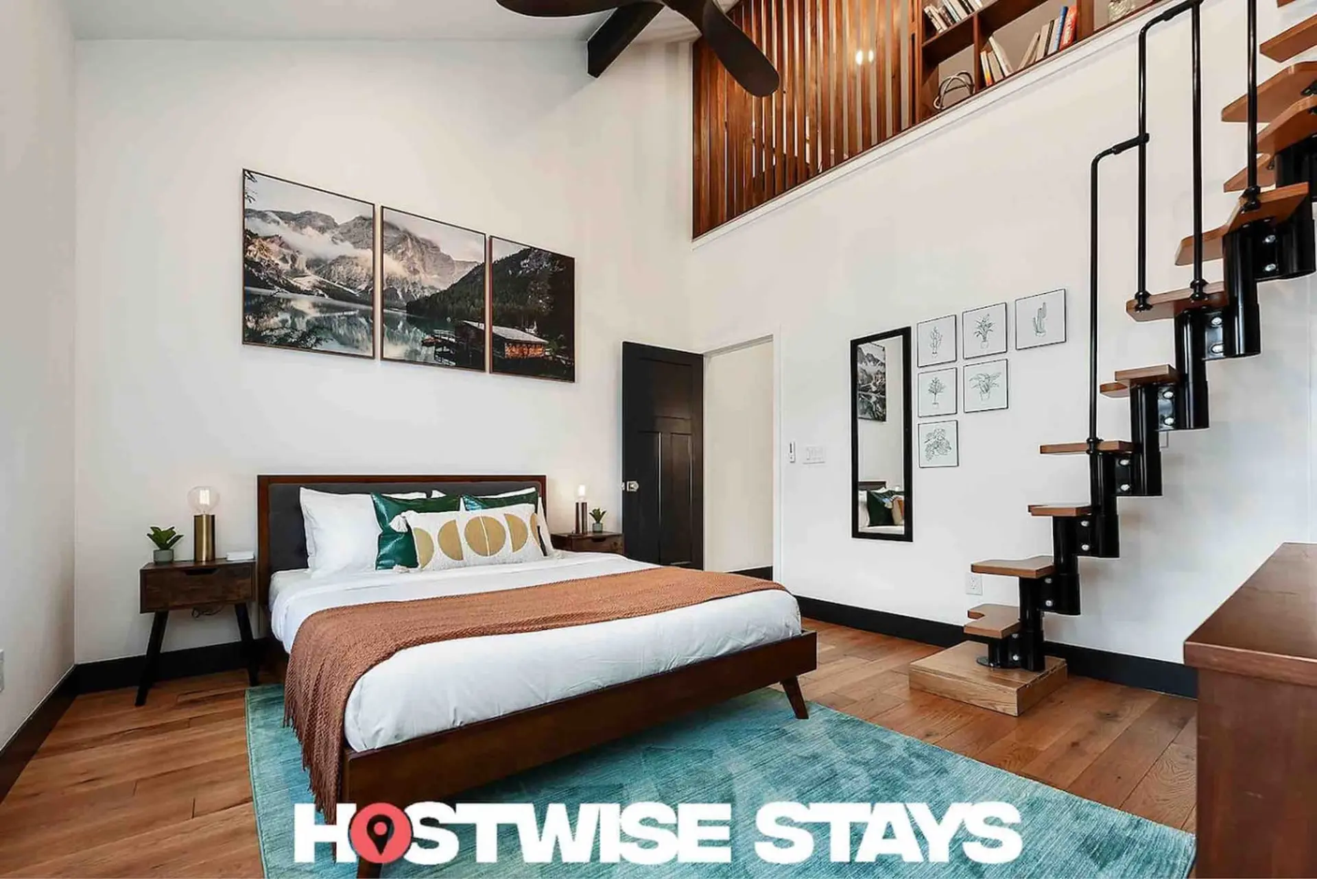 Bedroom with loft stairs and mountain artwork.