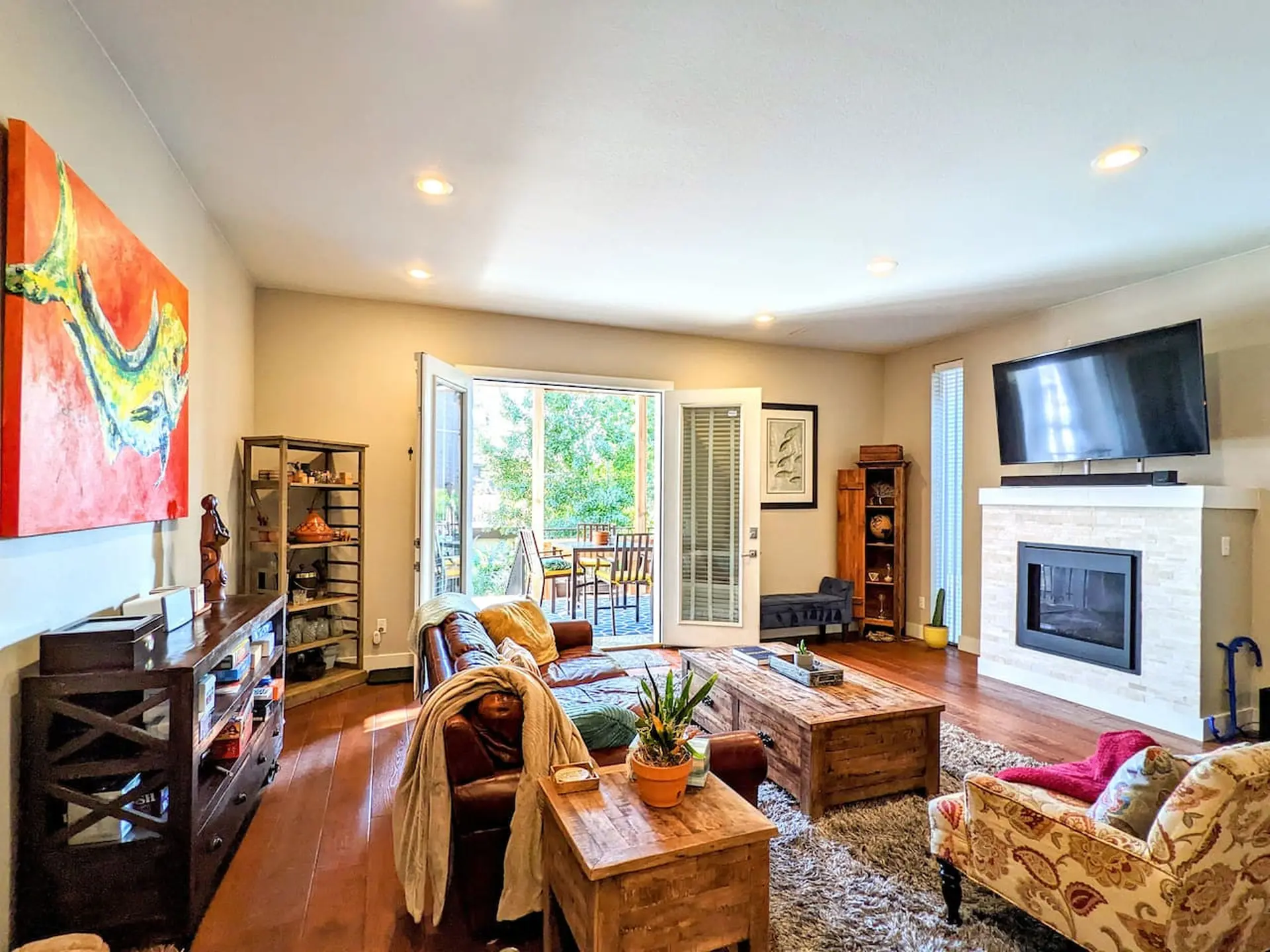 A living room with a leather couch, wooden coffee table, fireplace, and TV.
