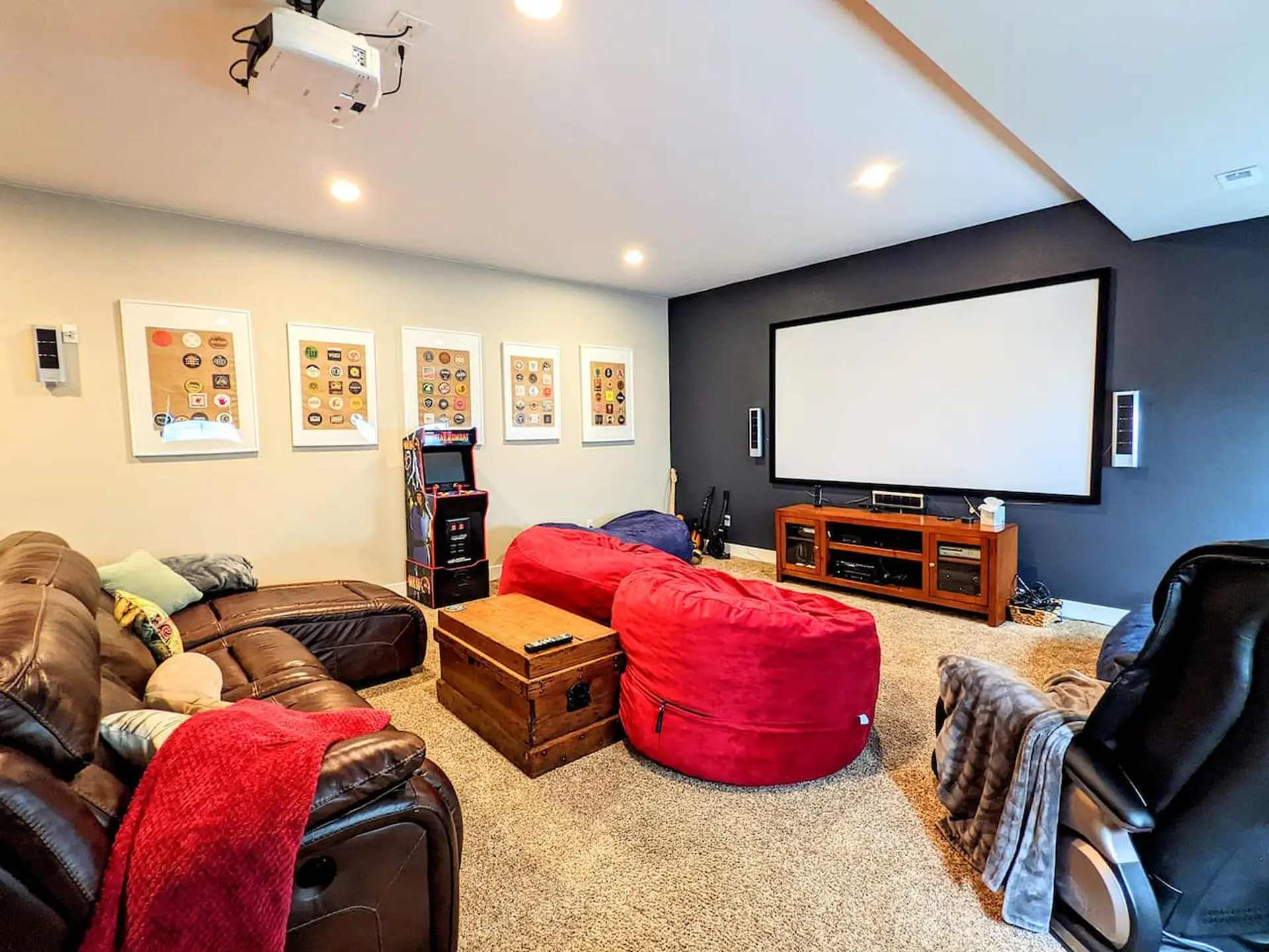 A home theater with a large projector screen, beanbag chairs, and a leather couch.