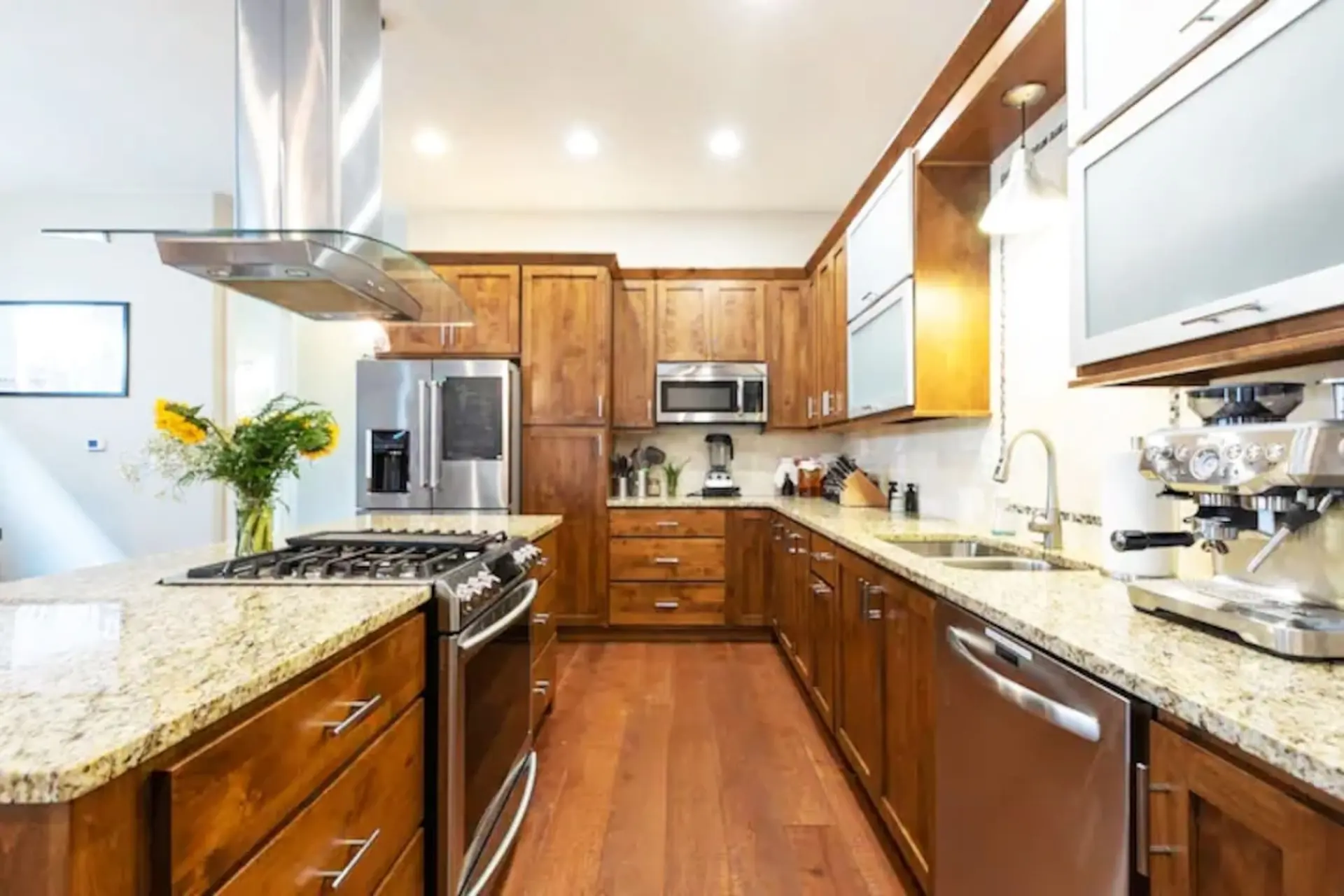 A modern kitchen with stainless steel appliances, granite countertops, and wooden cabinets.