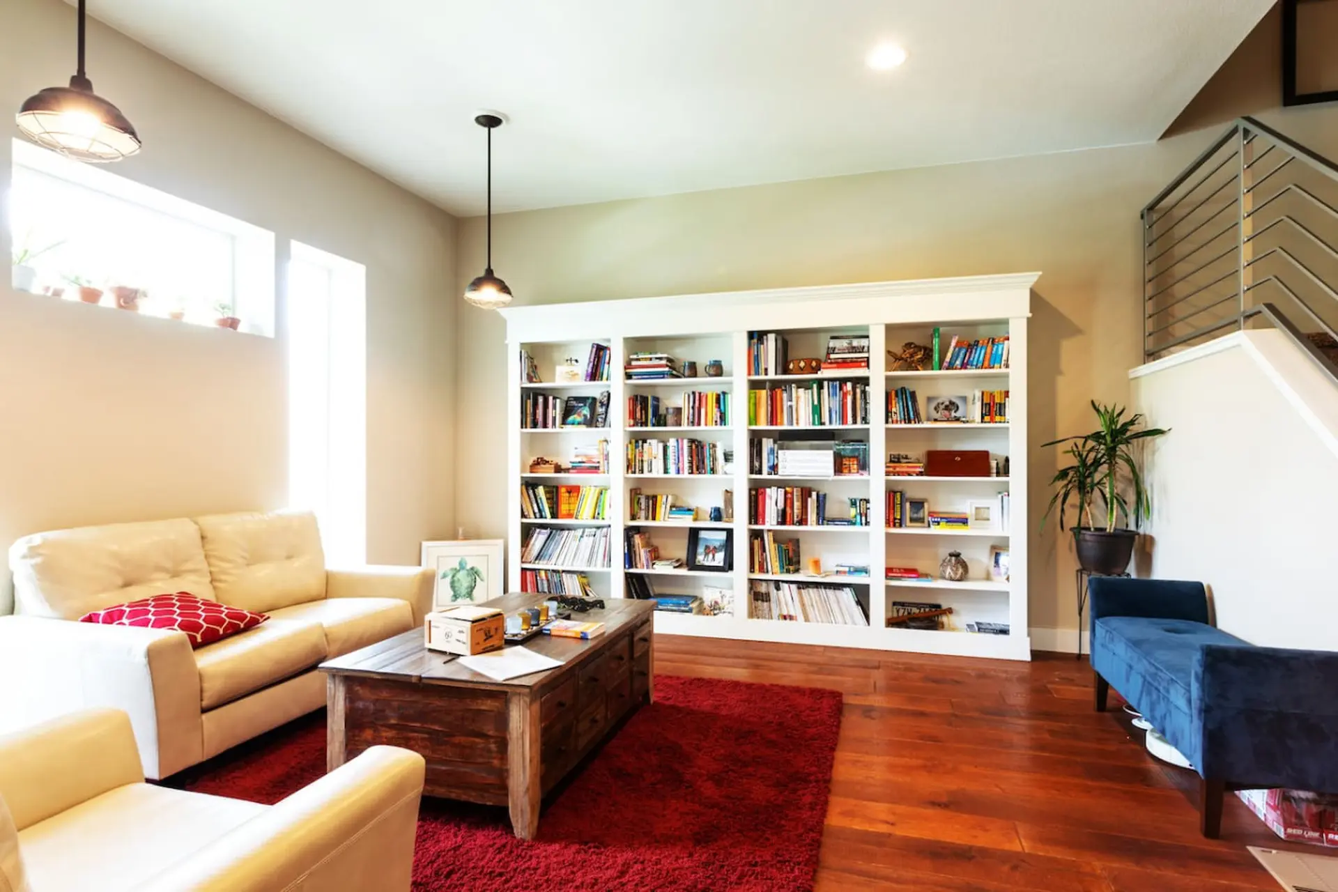 Living room with a large white bookshelf filled with books, a cream couch, and a wooden coffee table