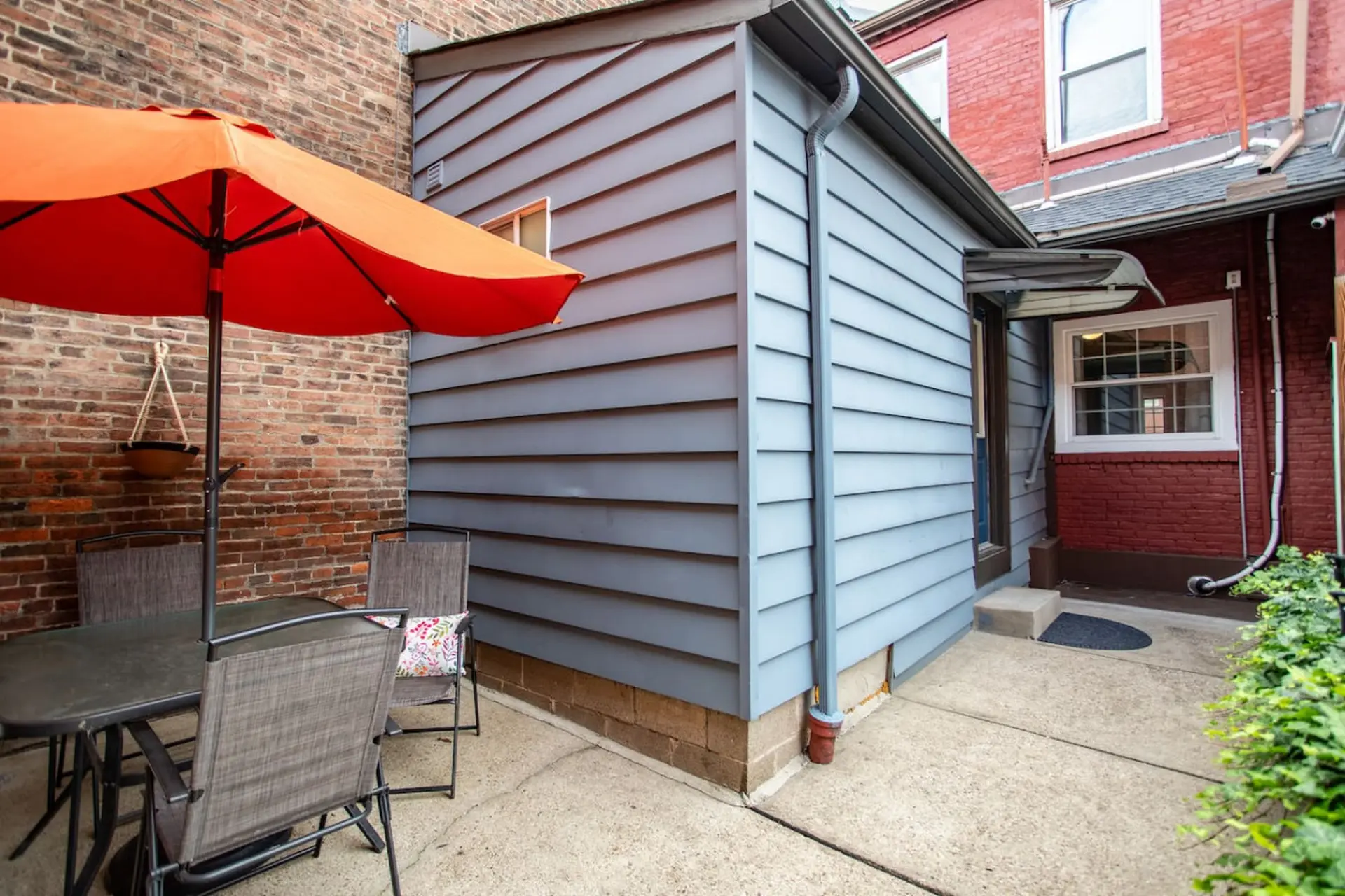 A patio with a table, chairs, and an umbrella next to a brick building.