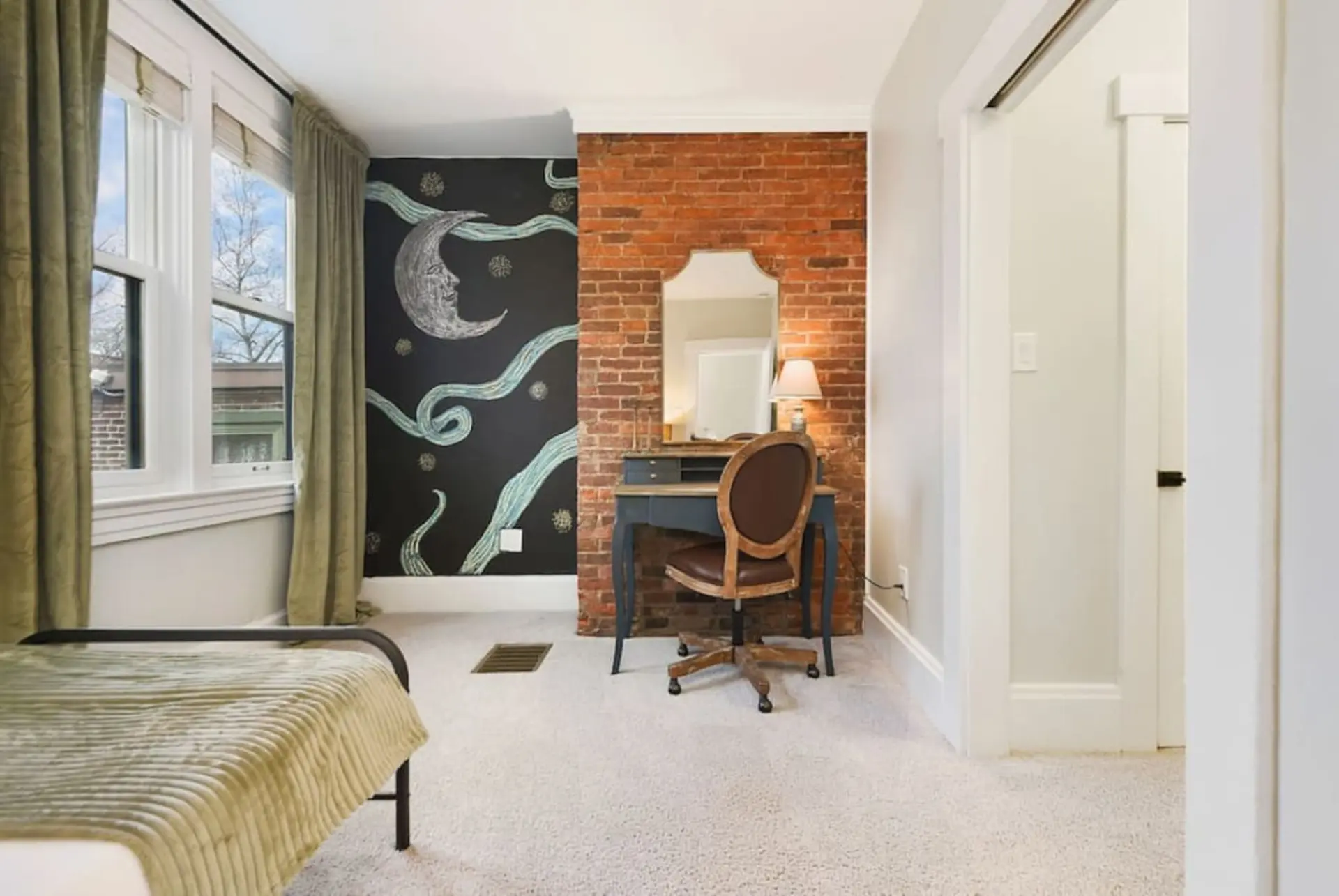 Bedroom with a desk, chair, and a chalkboard wall with a moon design.