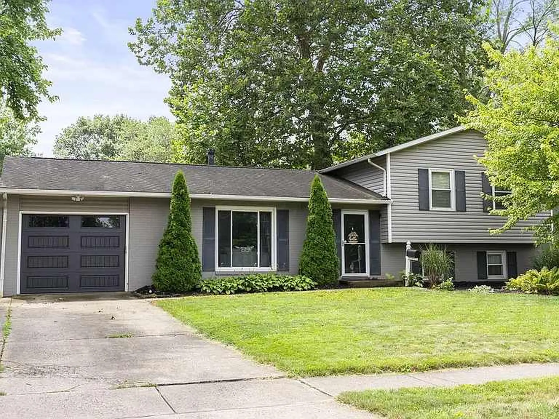 A grey house with a garage and a well-maintained lawn.