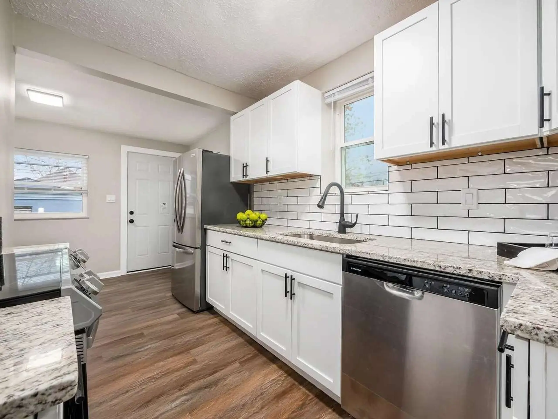 A modern kitchen with white cabinets, stainless steel appliances, and a subway tile backsplash.