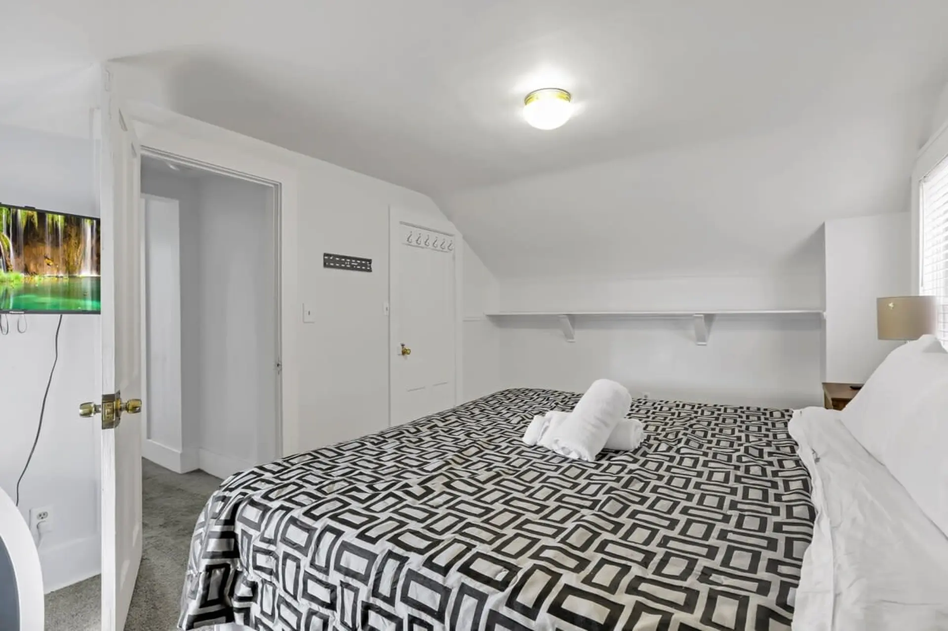 A bed with a black and white geometric pattern blanket and rolled towels.