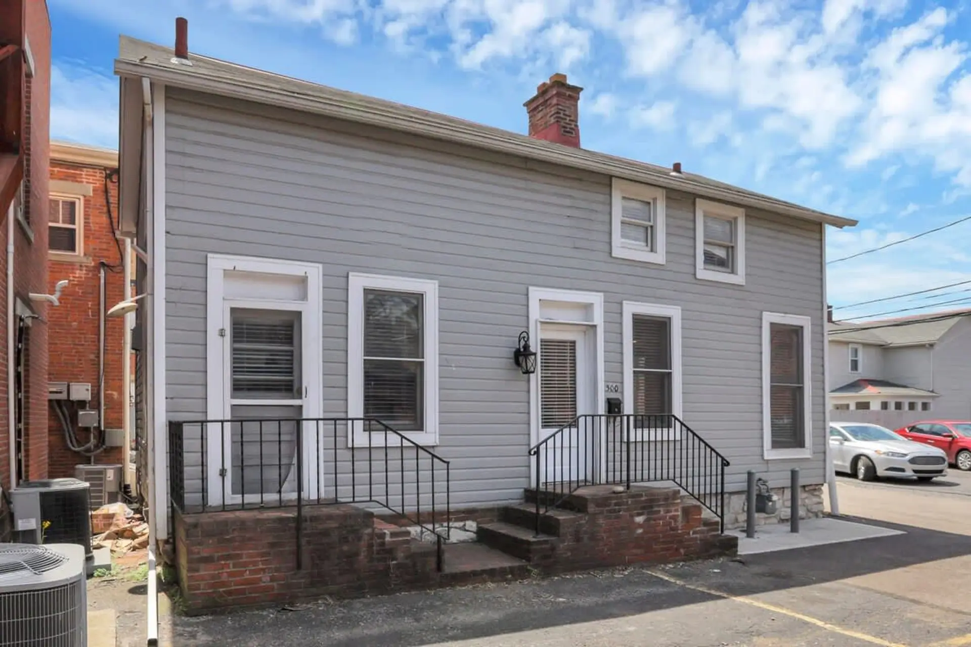 A gray, two-story house with white trim and windows.