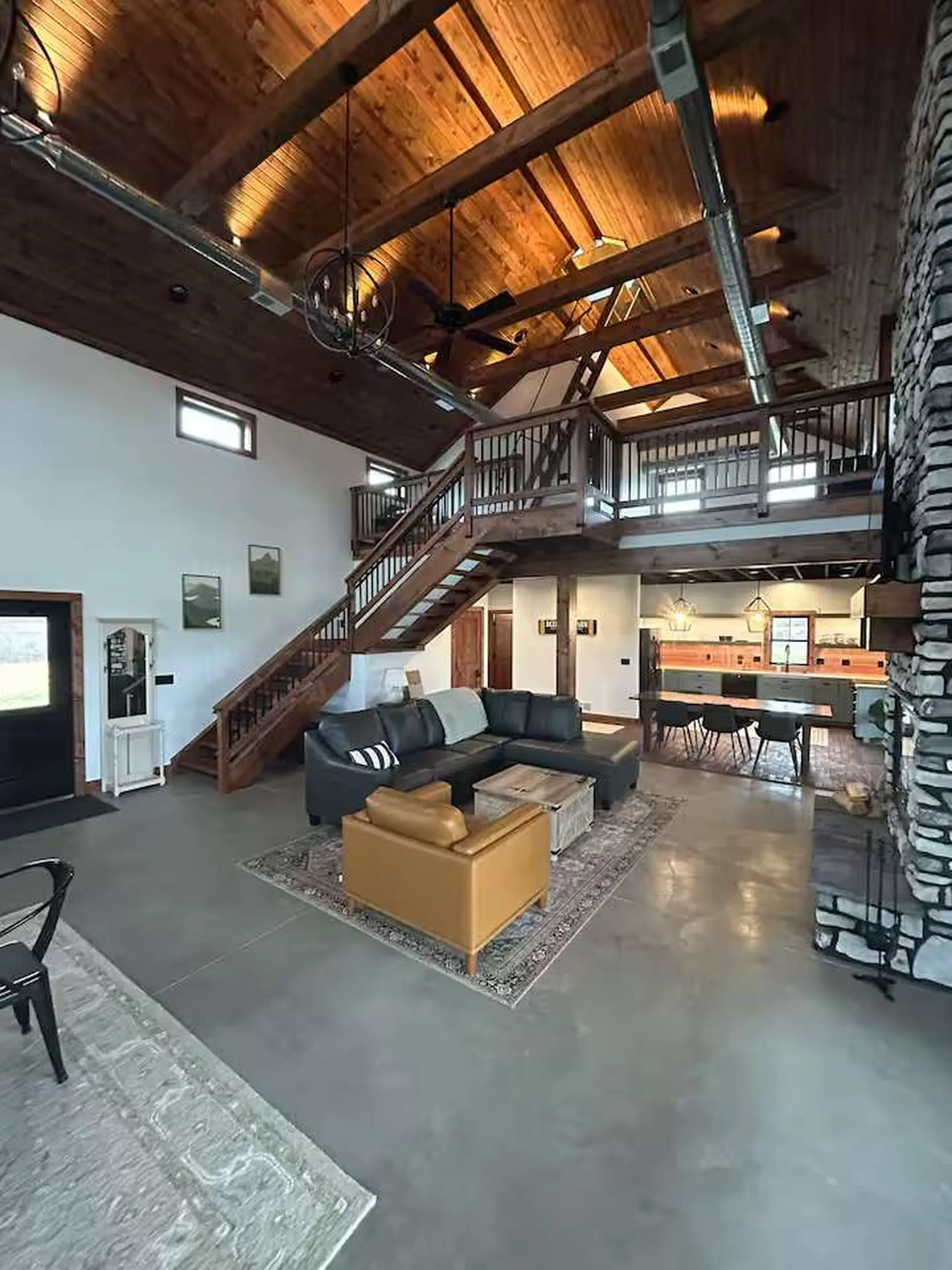 A spacious living area with a sectional sofa, leather accent chair, and a stone fireplace.