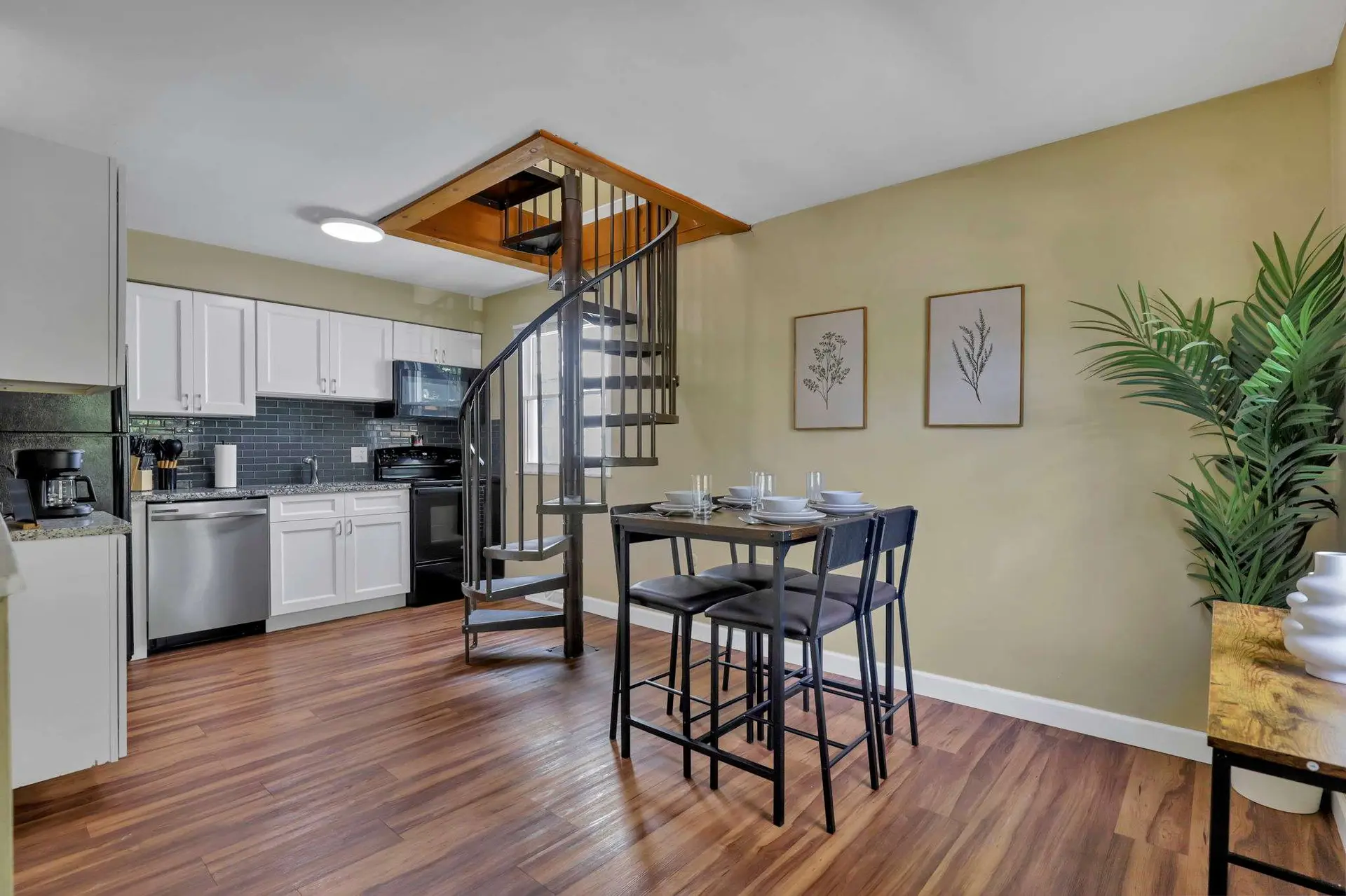 Kitchen with spiral staircase and dining table with chairs.