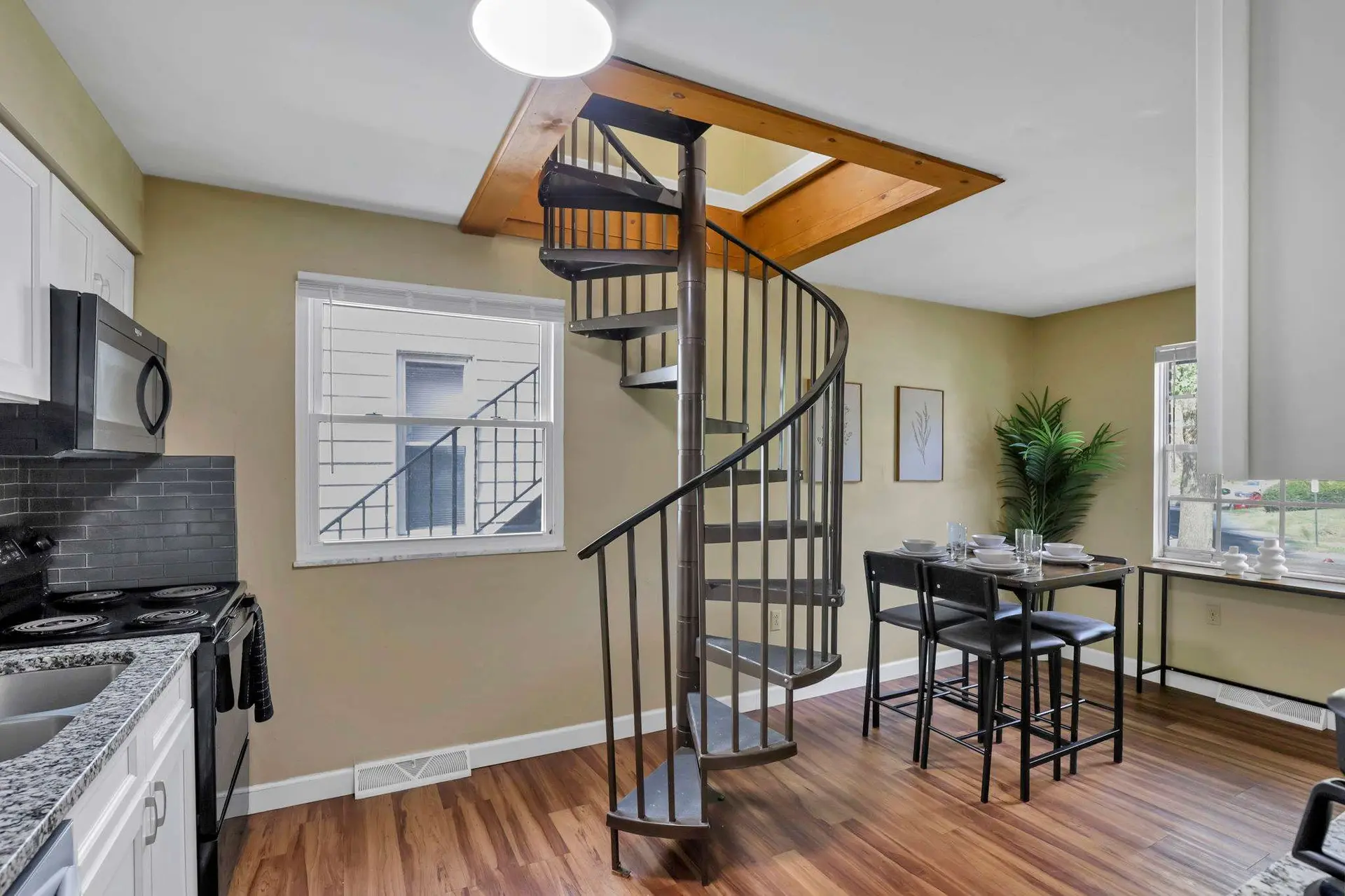 A stylish dining area with a spiral staircase and a well-equipped kitchen.