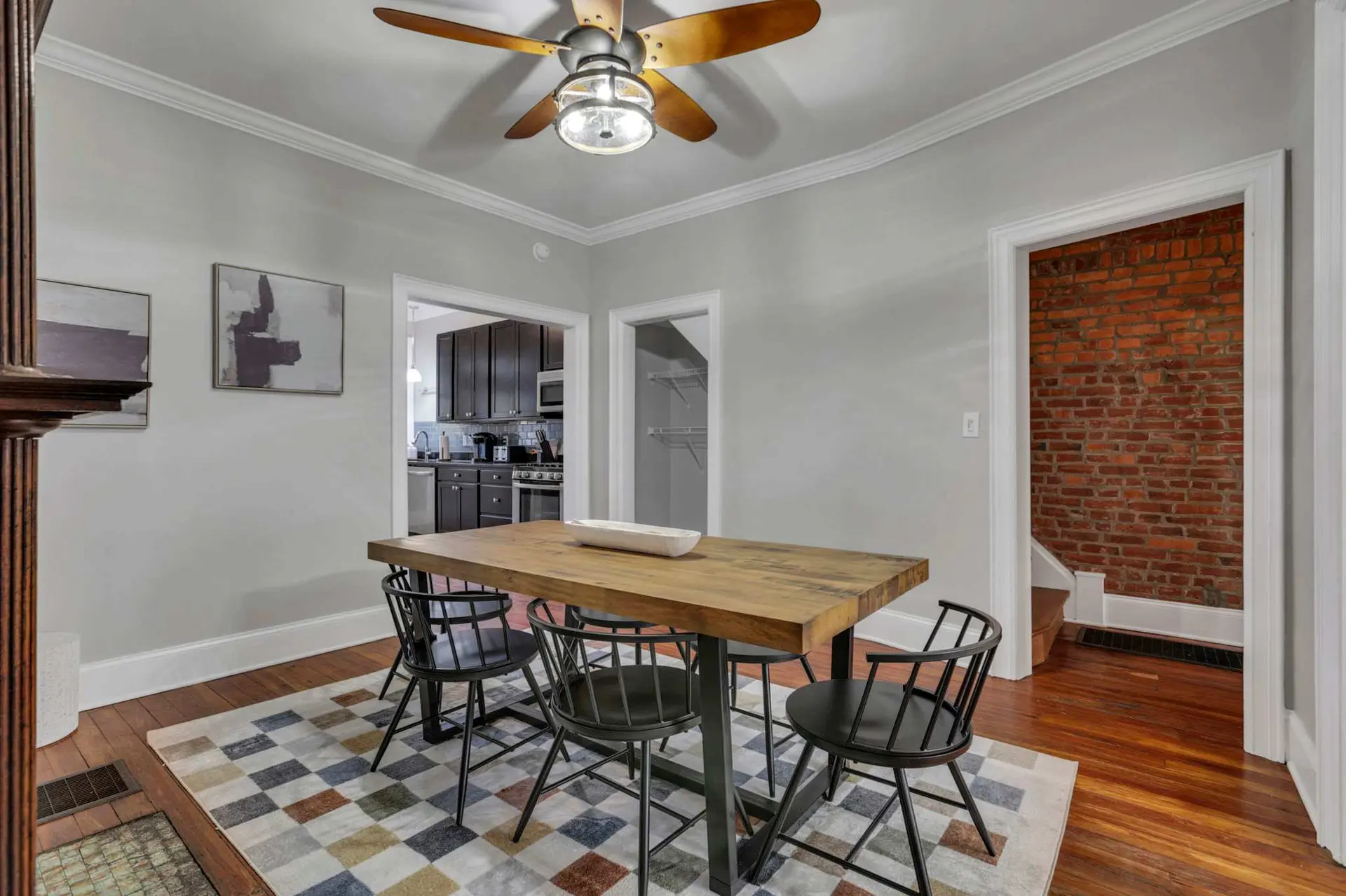 A dining room with a wooden table, chairs, and a geometric rug.