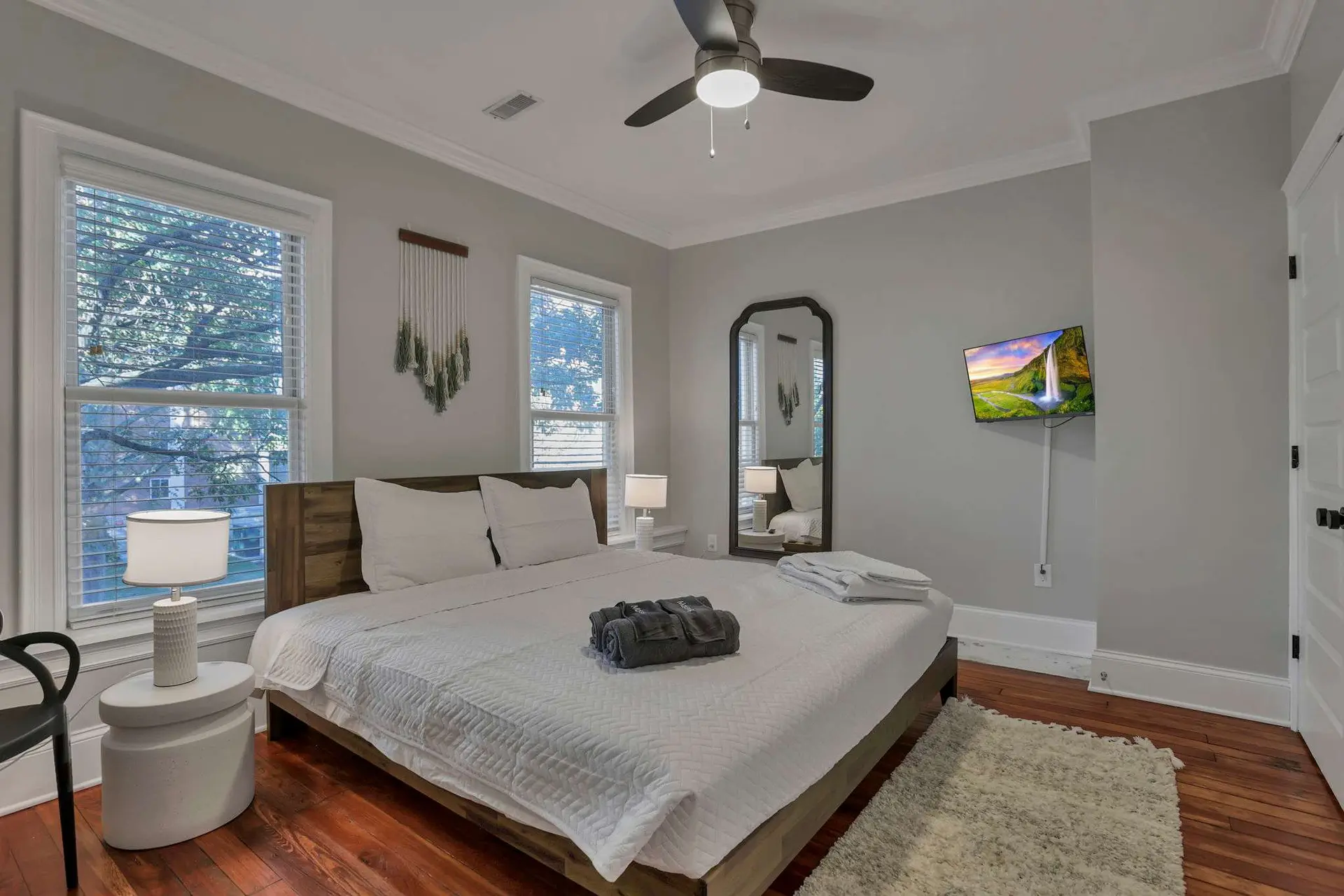 A minimalist bedroom with a large bed, wooden floor, and a TV.