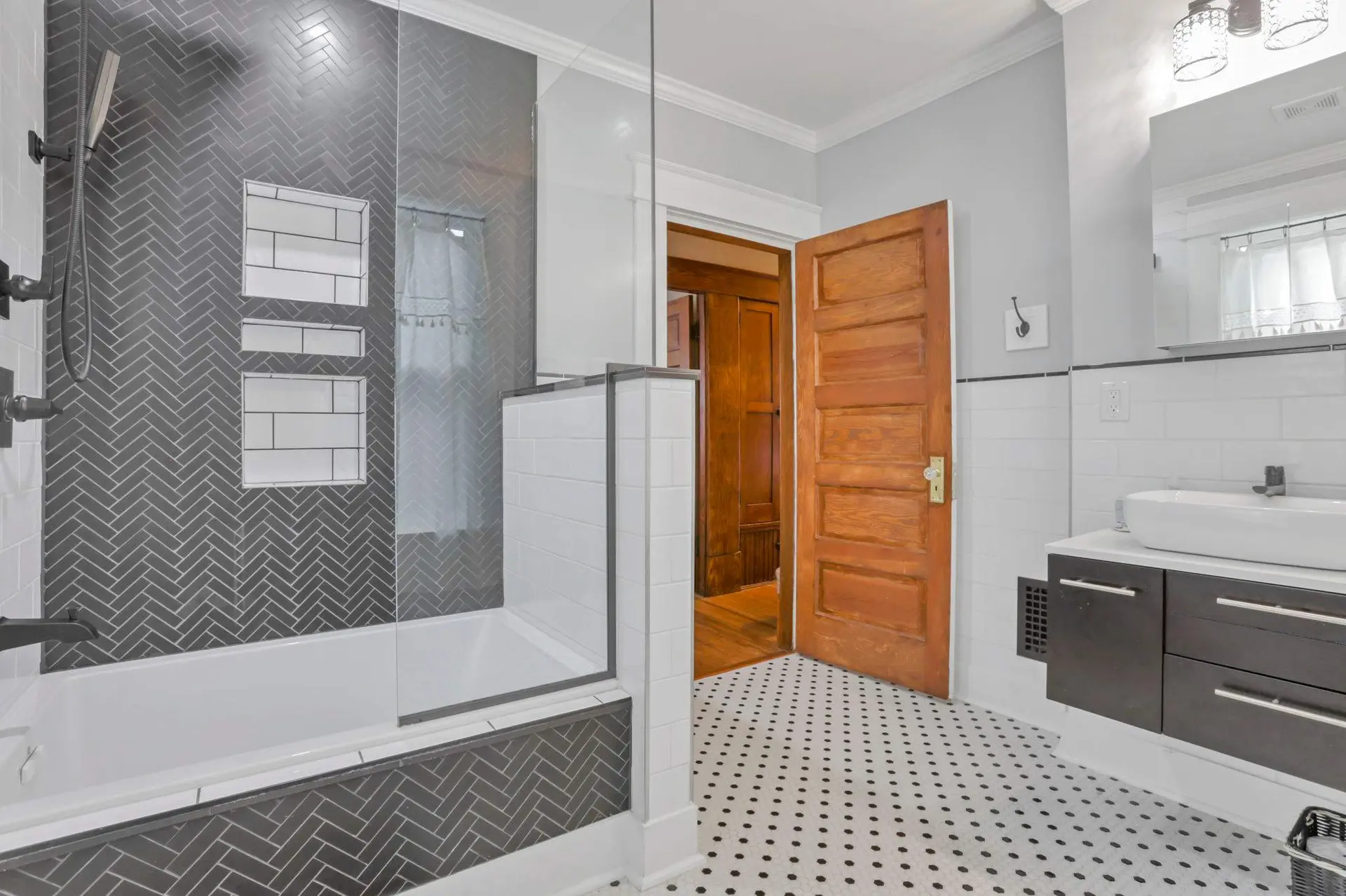A modern bathroom with a bathtub, a vanity, and a wooden door.