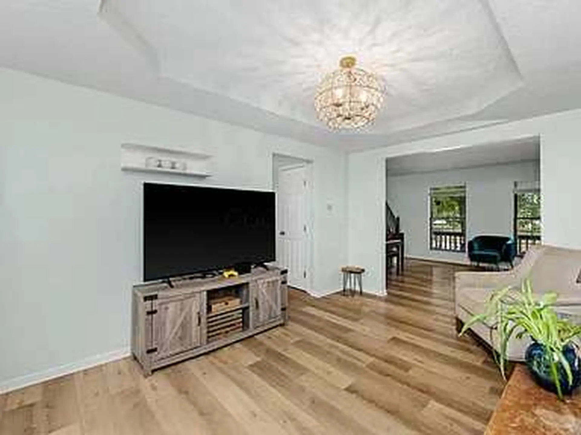 The living room features a large black television on a rustic media console, a plush beige sofa, and