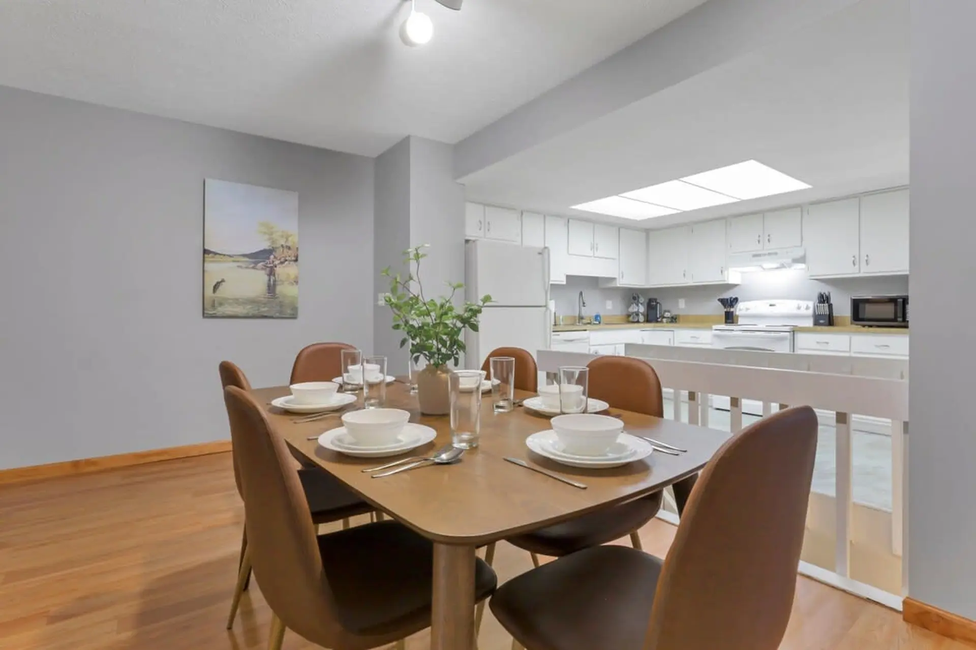 Dining room with a table set for dinner and a kitchen in the background.