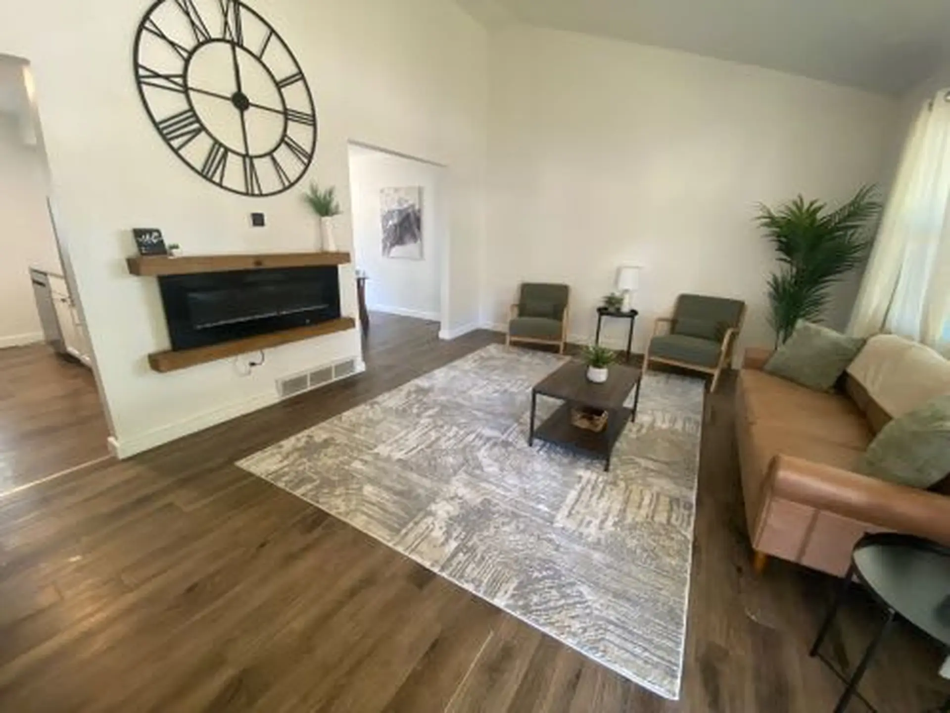 A living room with a fireplace, a large clock, and furniture.