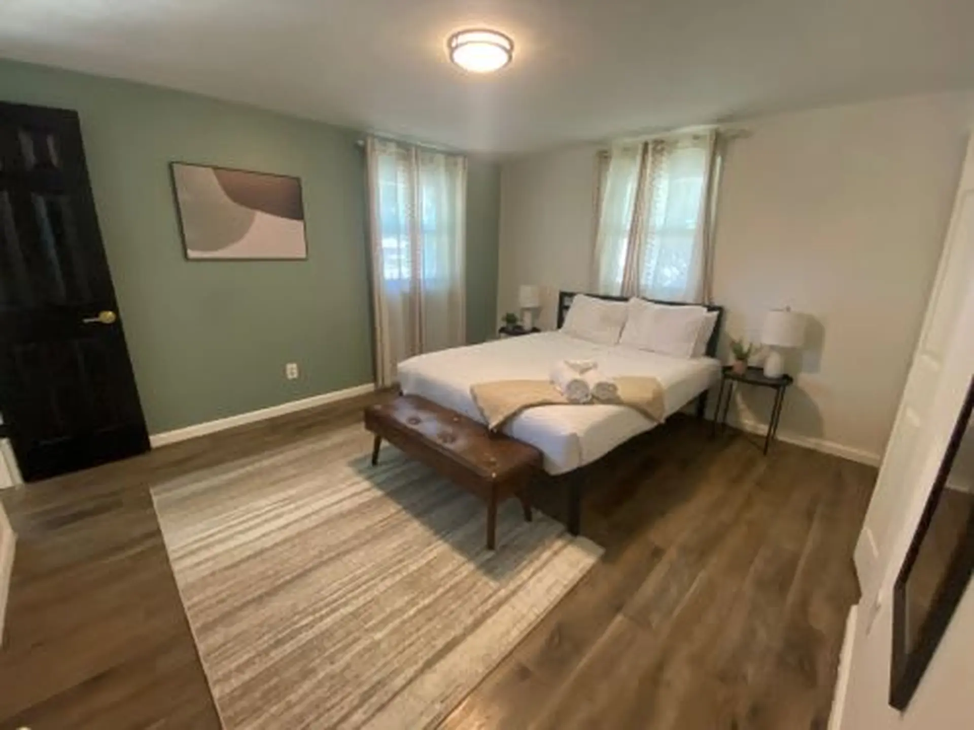 A bedroom features a bed, a dresser, and a dark wood door.