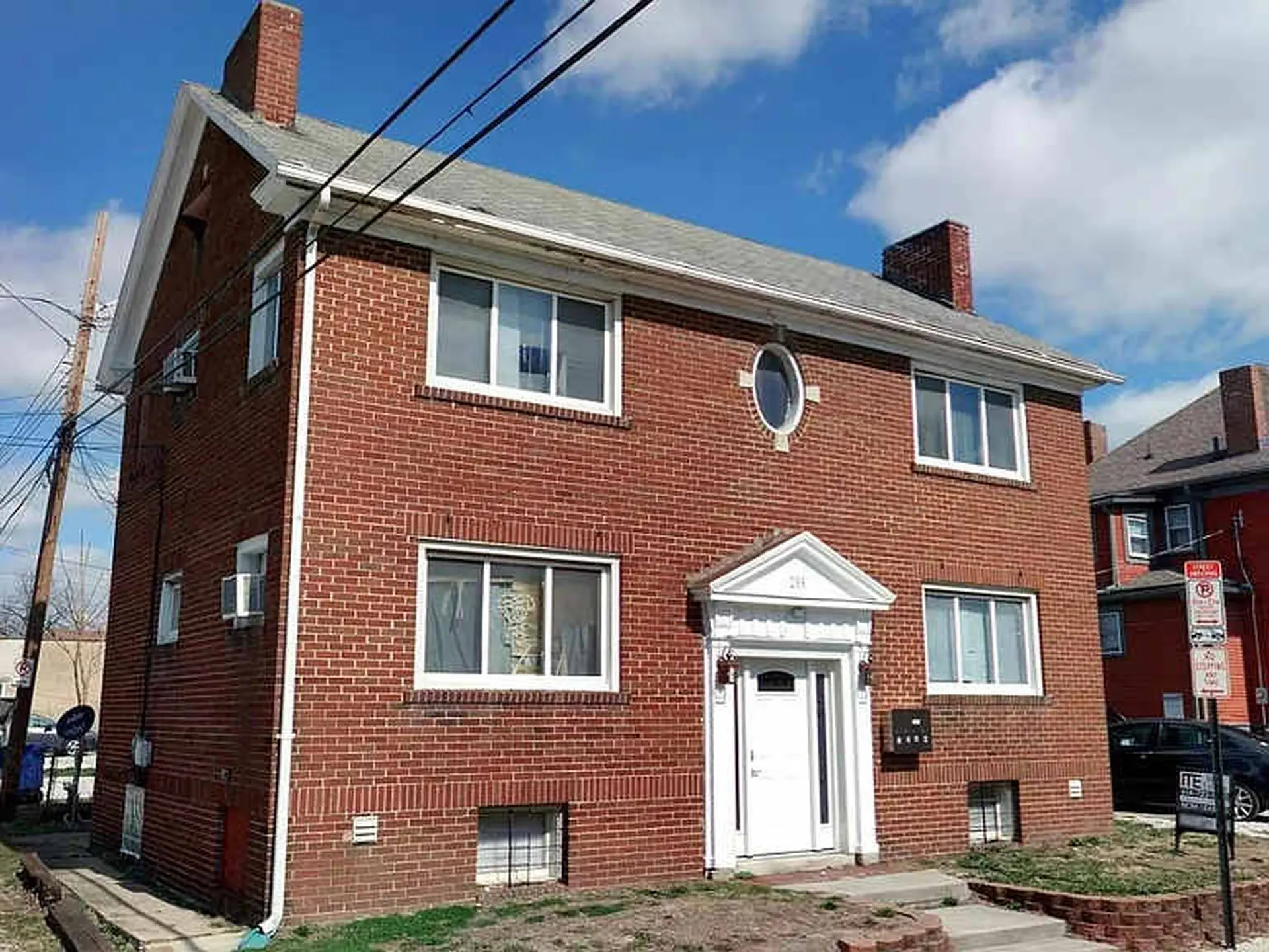 A brick building with multiple windows and a white door.