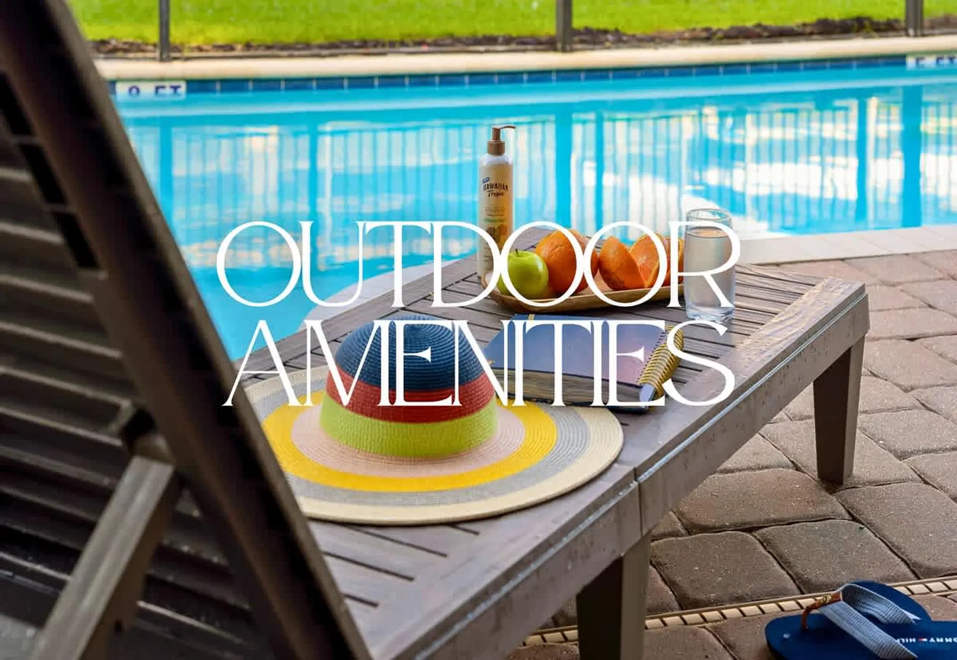 Outdoor amenities including a hat, fruit, and drinks by a pool.