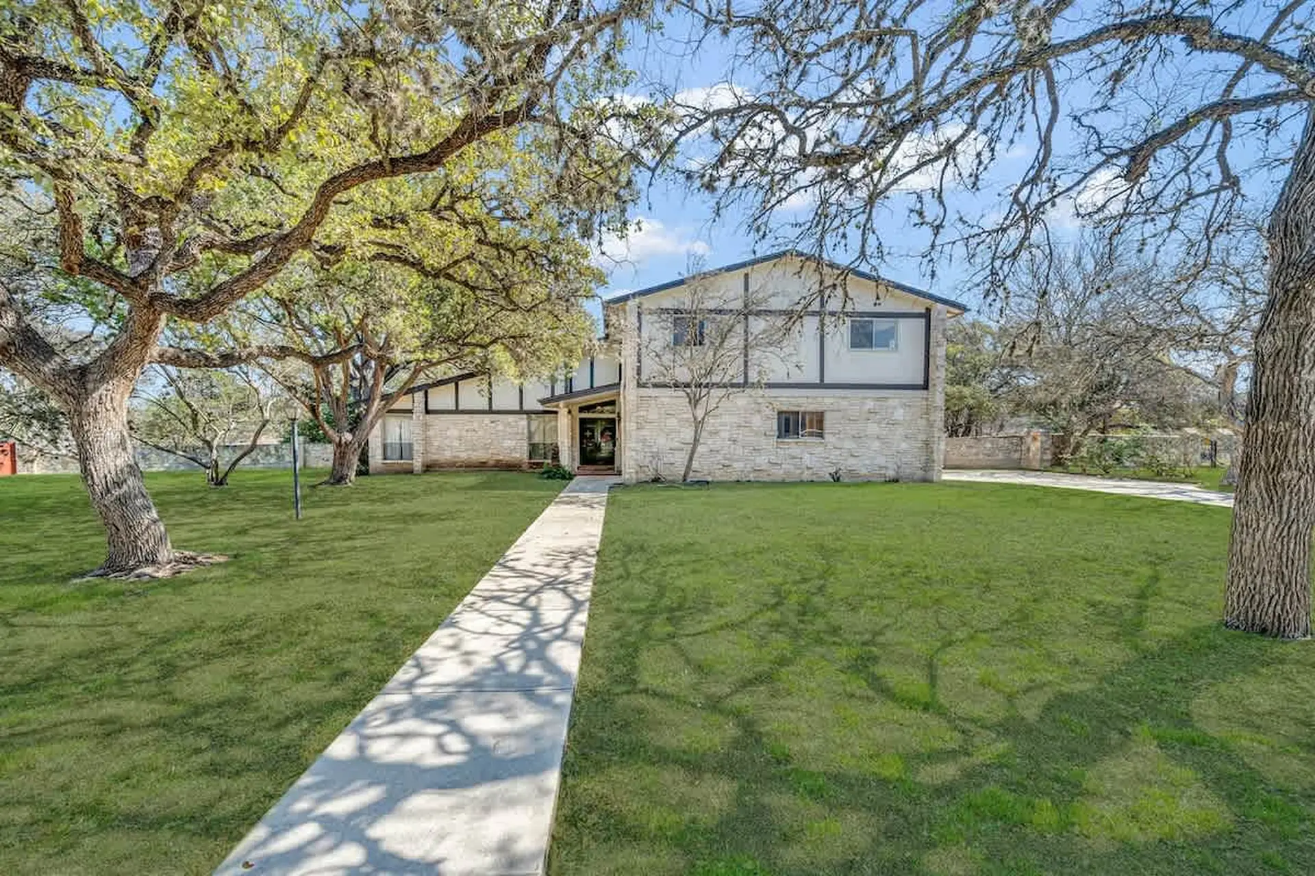 A modern two-story house with white stone and dark wood accents.