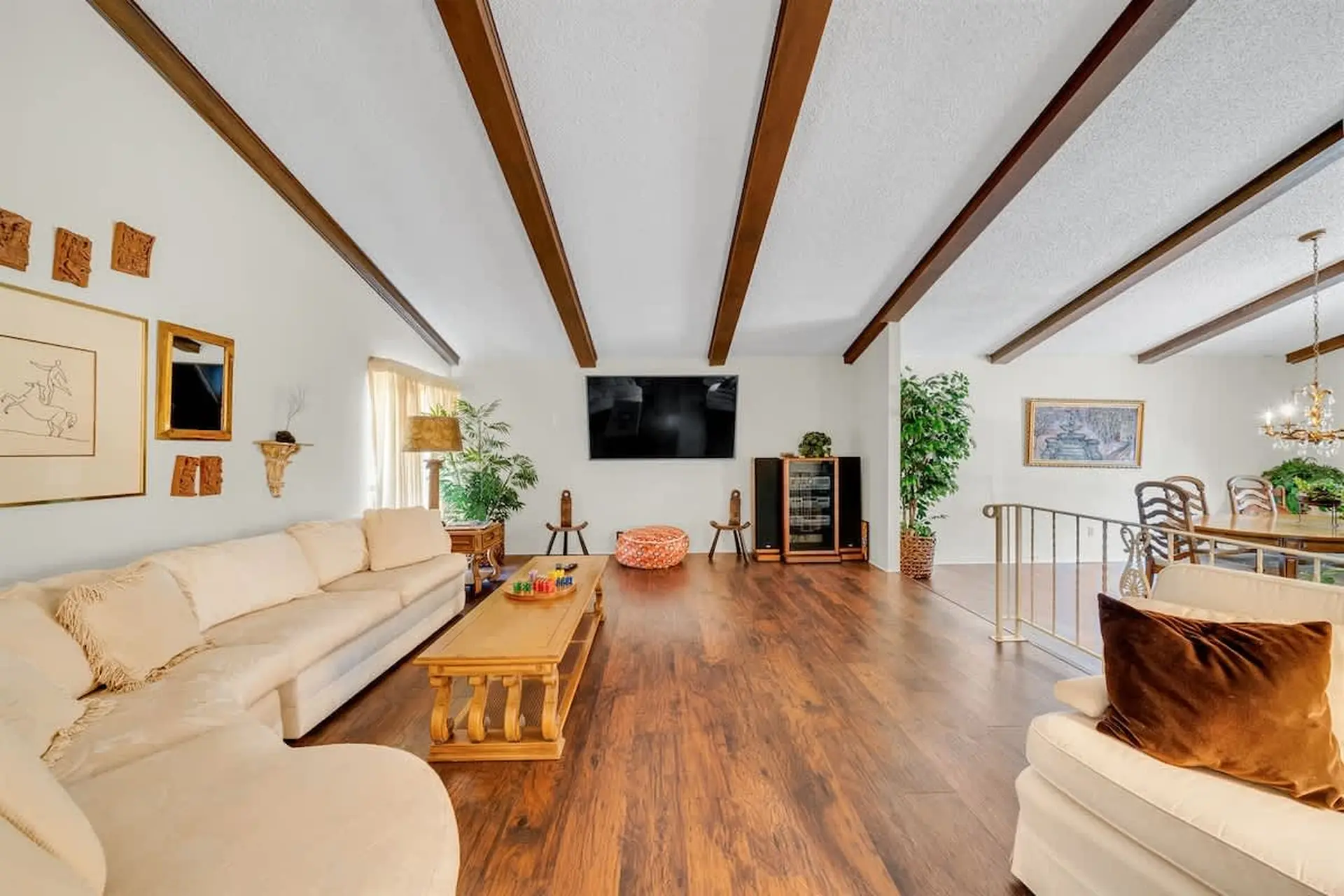 Living room with a sectional sofa, coffee table, TV, and a dining area.