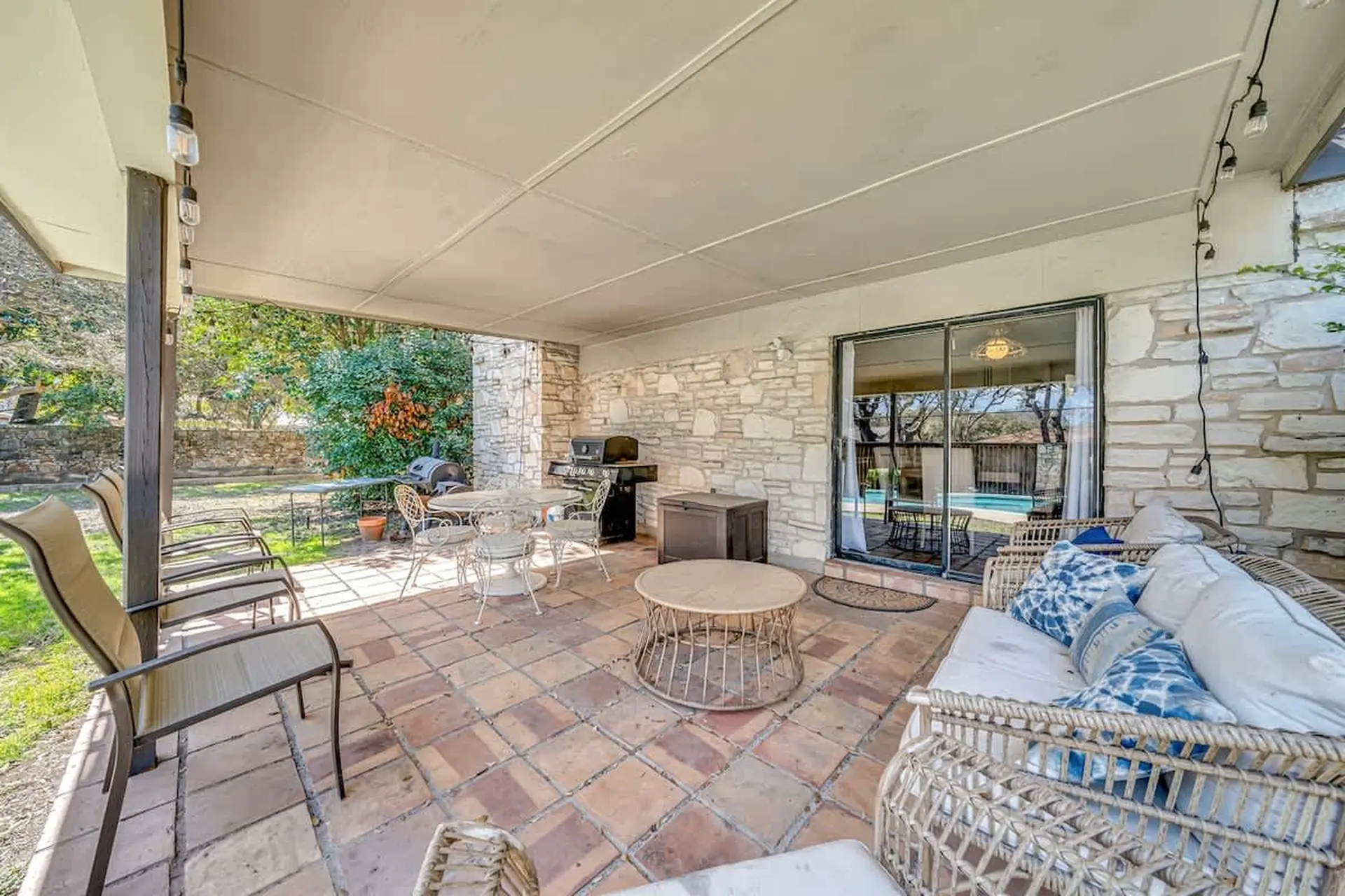 A covered patio with a dining set, grill, and lounge seating.