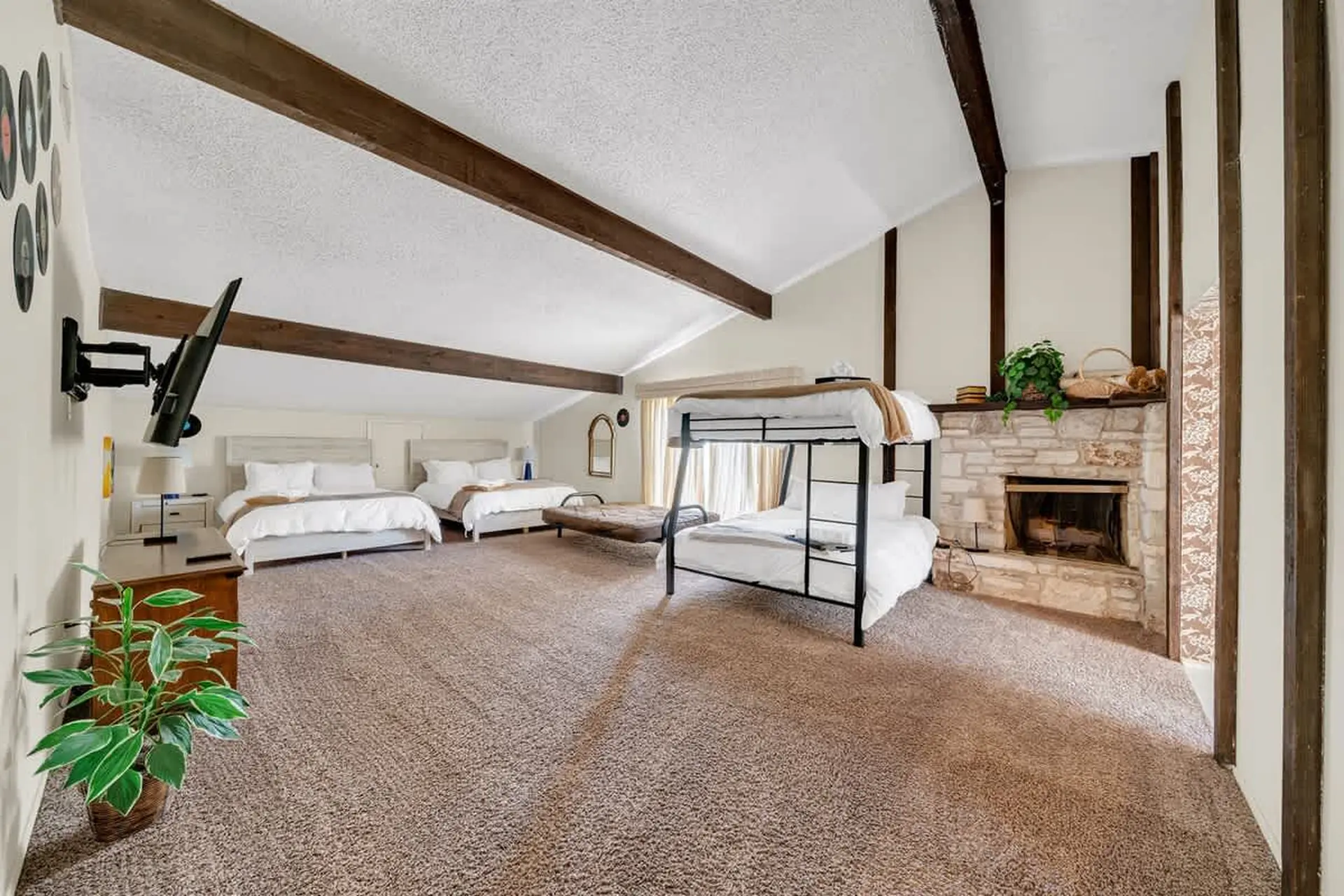 A bedroom with two beds, a bunk bed, and a fireplace.