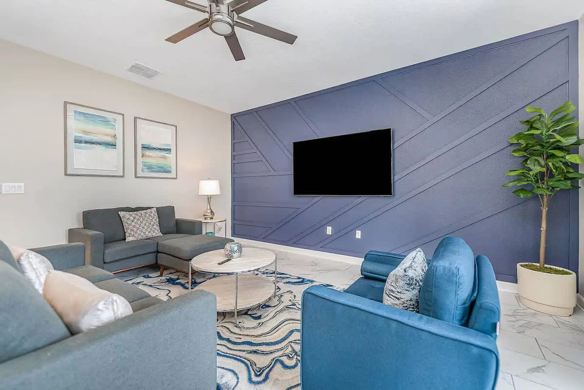 Living room with blue sofa, geometric accent wall, and TV.