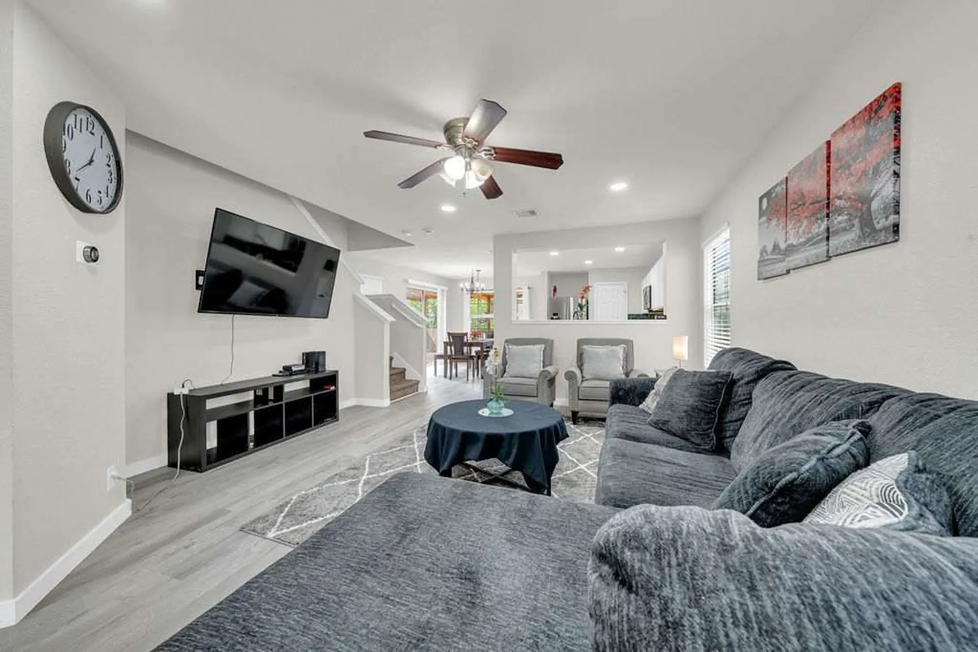 A spacious living room with a dark gray sectional, chairs, and a round table.