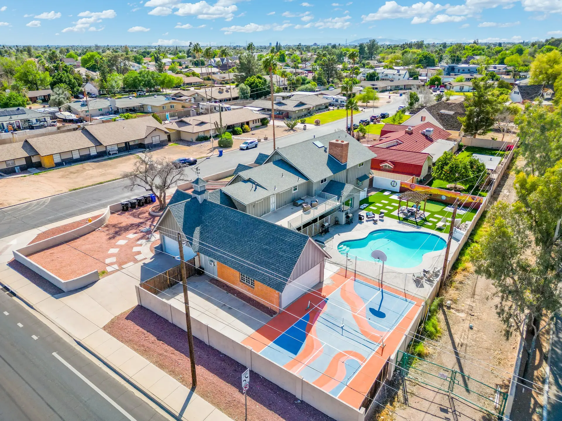 Aerial view of a suburban neighborhood with houses, a pool, and a basketball court.