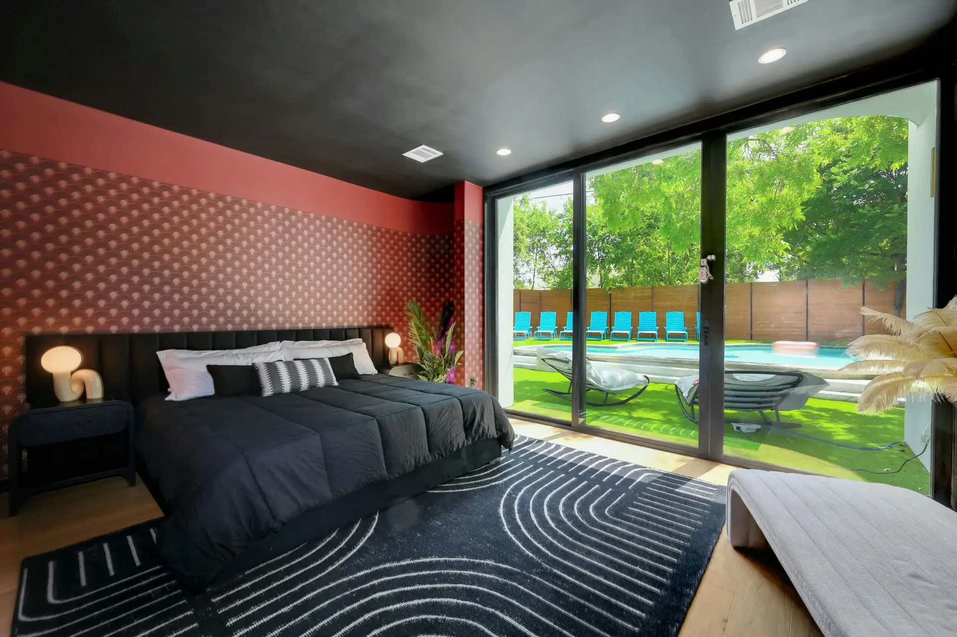 Bedroom with a large window overlooking a pool and lounge chairs.