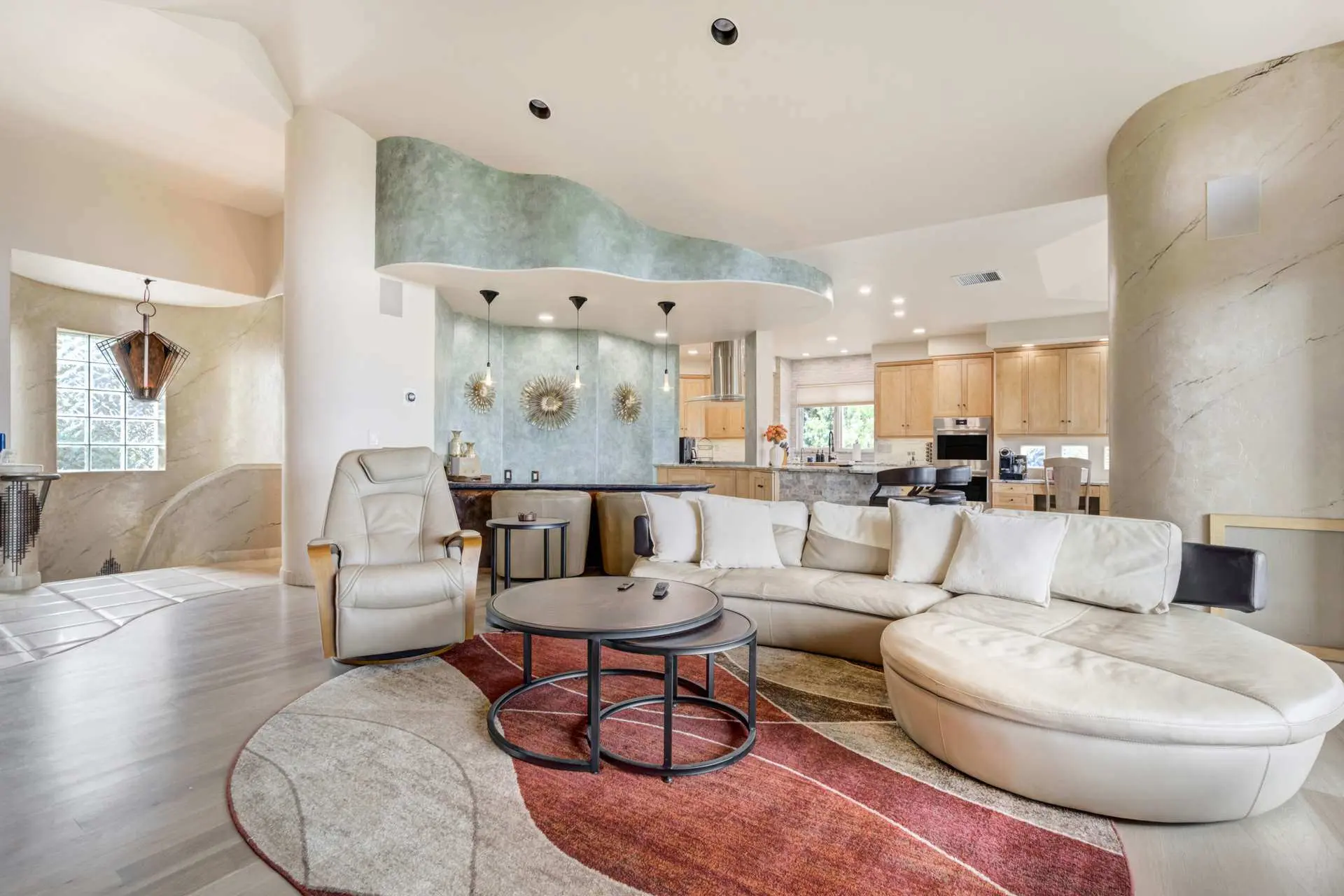 A spacious living room and kitchen area with modern furniture and a curved ceiling.