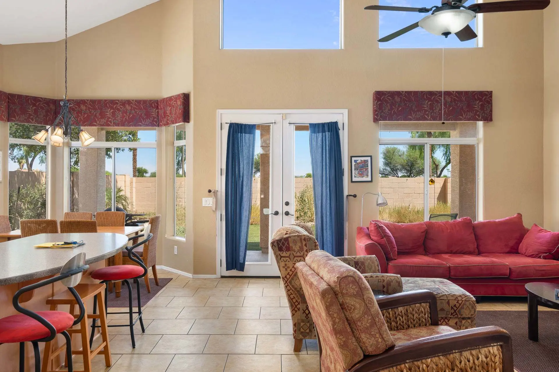 A living room with a red couch, two patterned chairs, and a breakfast bar.